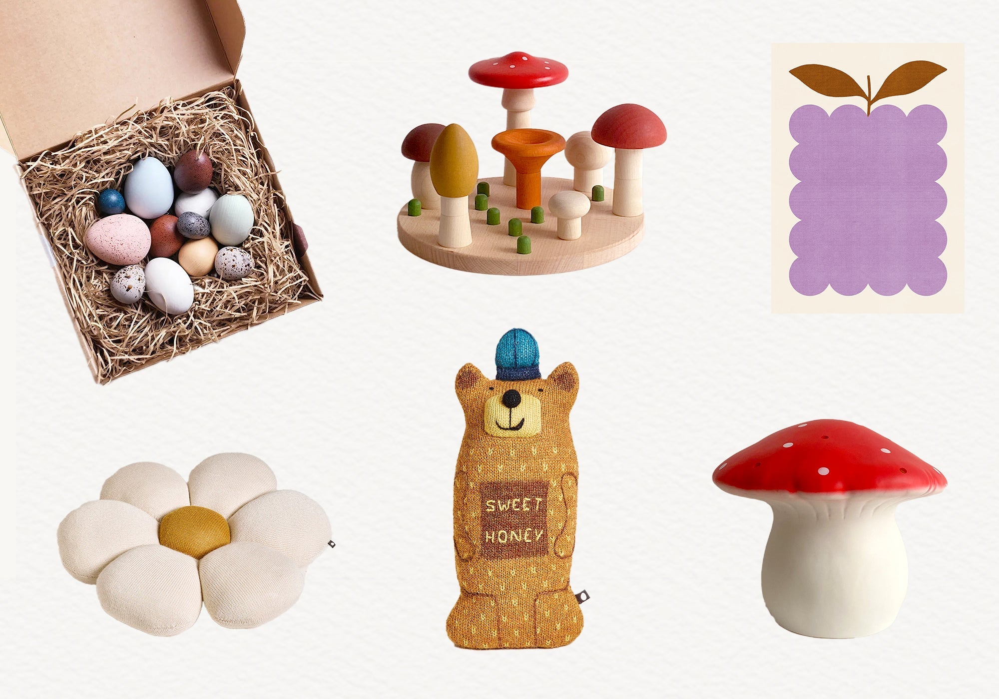 Assorted cute toys and decor: wooden mushrooms, fabric flower, plush bear, spotted mushroom, eggs, and art print.