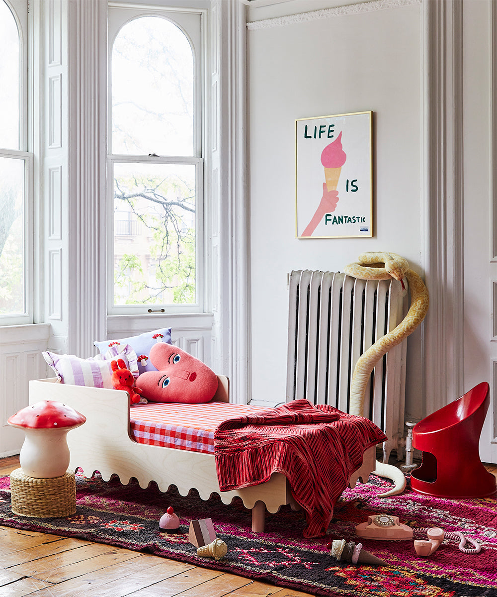Children's room with a bed, toys, decor, a Heart Pillow, "Life is Fantastic" poster on the wall, and arched windows in the background.