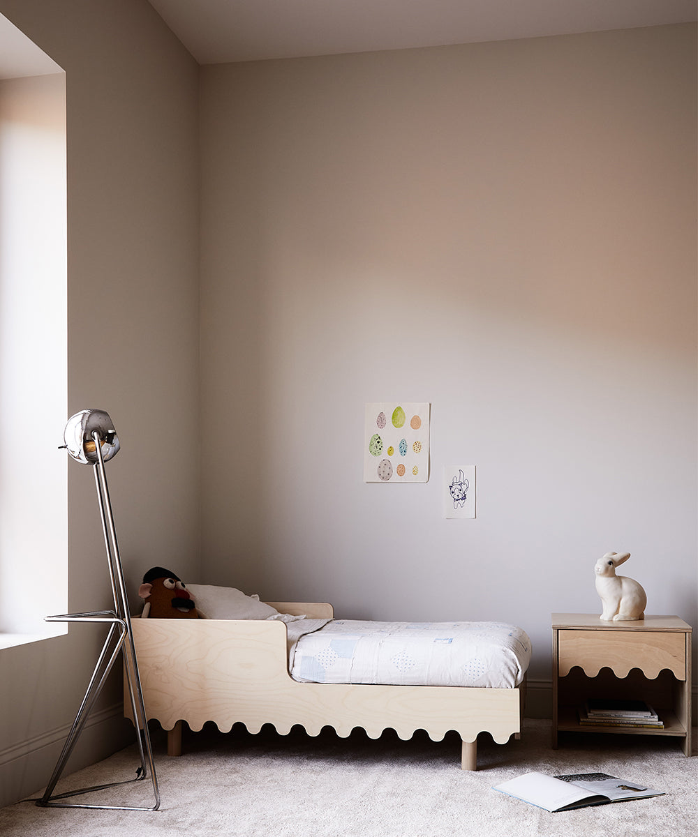 Minimalist childs bedroom featuring a Moss Toddler Bed, a stuffed toy, wall artwork, and a rabbit sculpture on the nightstand.