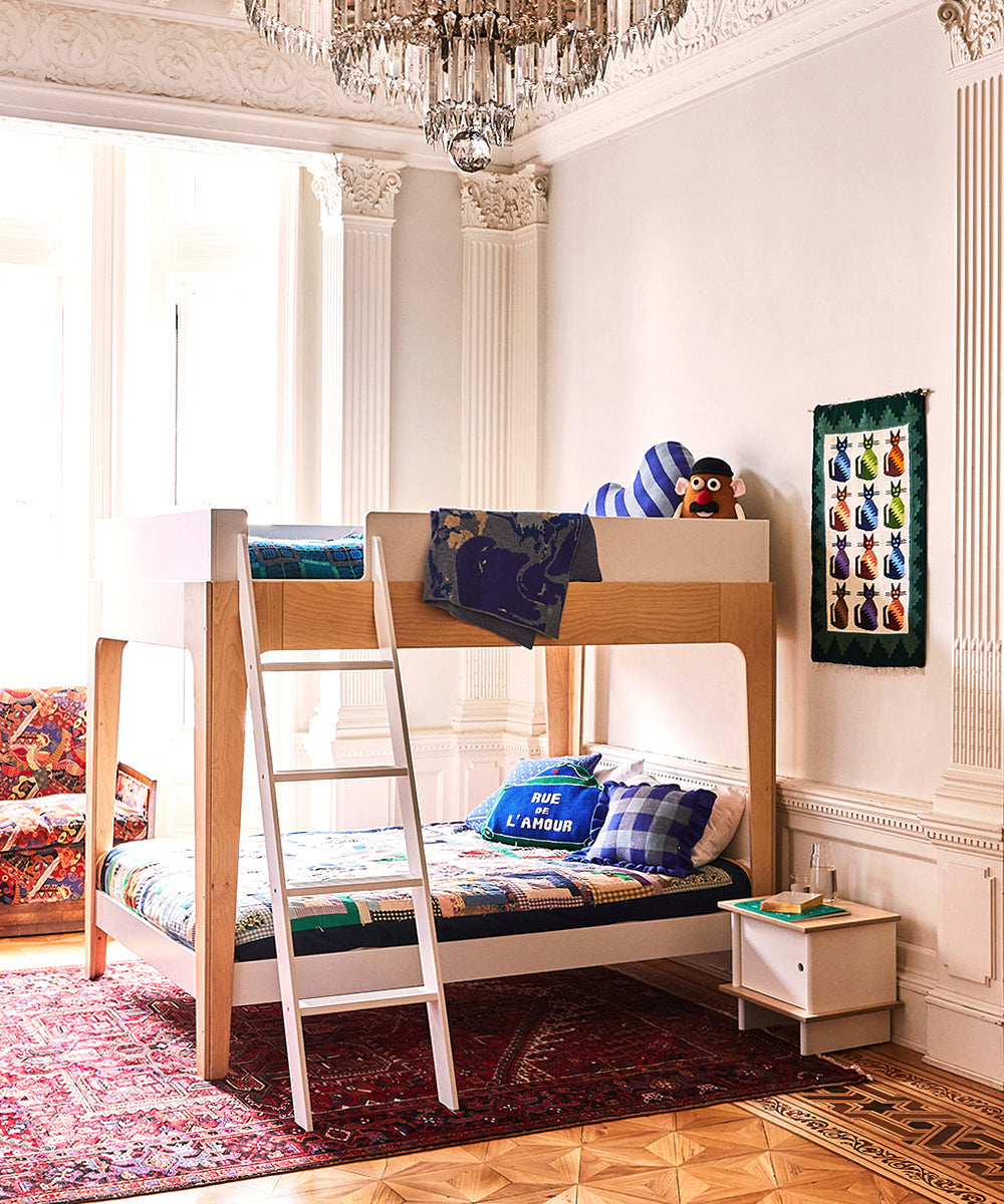 A childrens room featuring the Perch Full Bunk Bed, vibrant linens, cozy plush toys, and a patterned rug.
