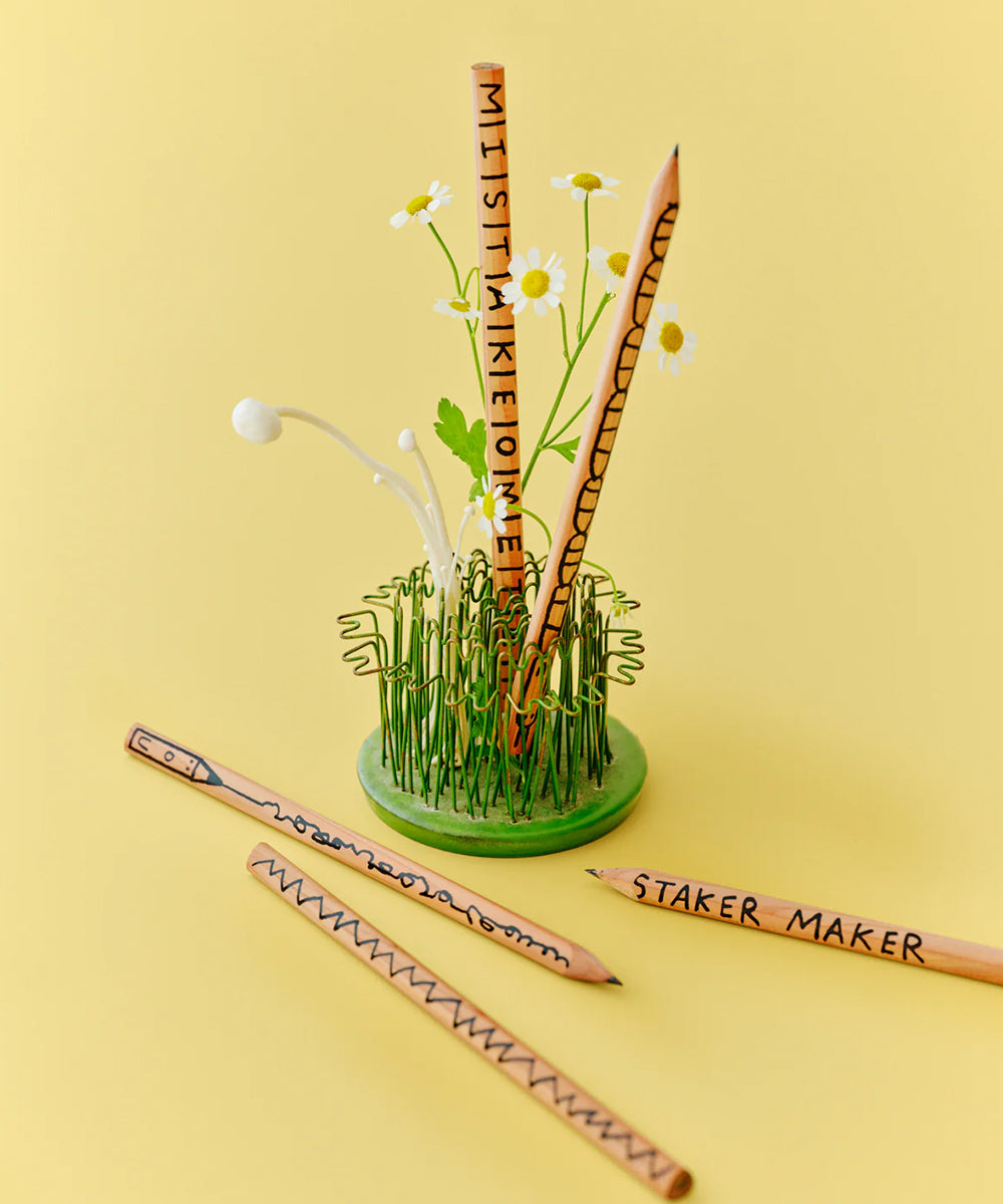 Five Le Mistake Maker Pencils, three in a flower-decorated green base and two on a yellow background, are displayed.