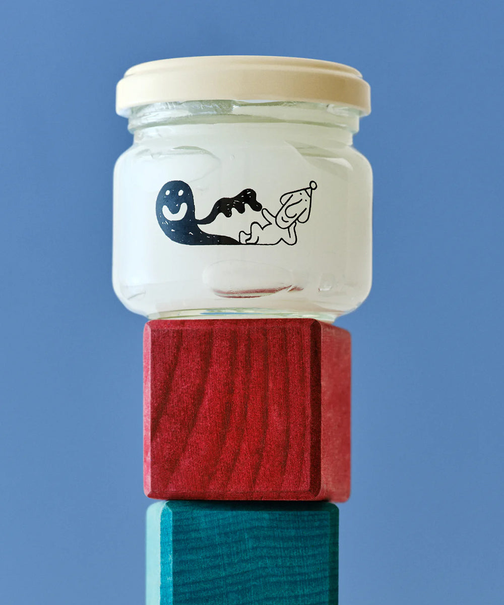 Le Gentle Scissors features a glass jar with a smiling black ghost and dog illustration, sitting on stacked red and blue wooden blocks.