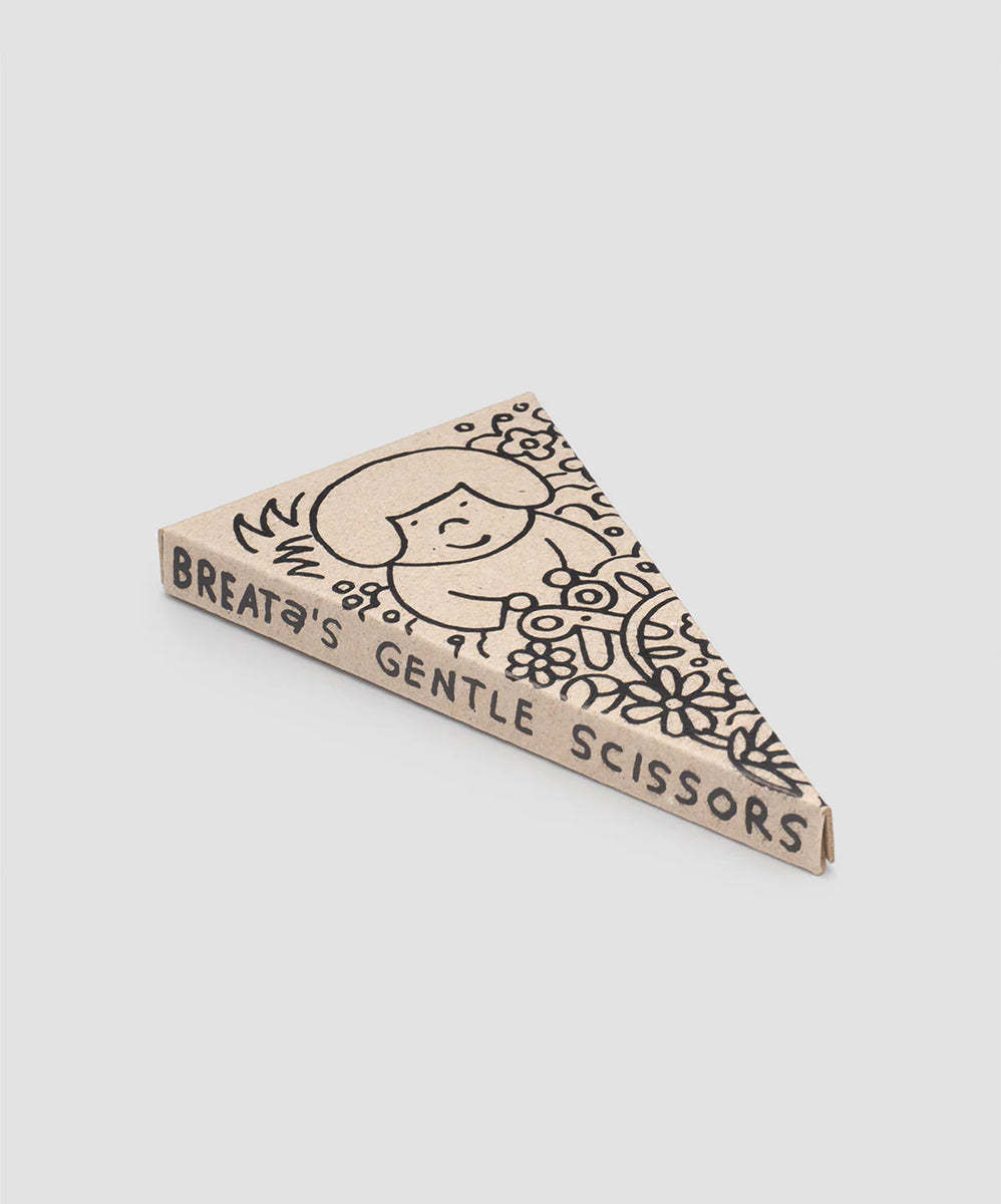 Triangular cardboard box with black illustration and text reading "Le Gentle Scissors" on the side.