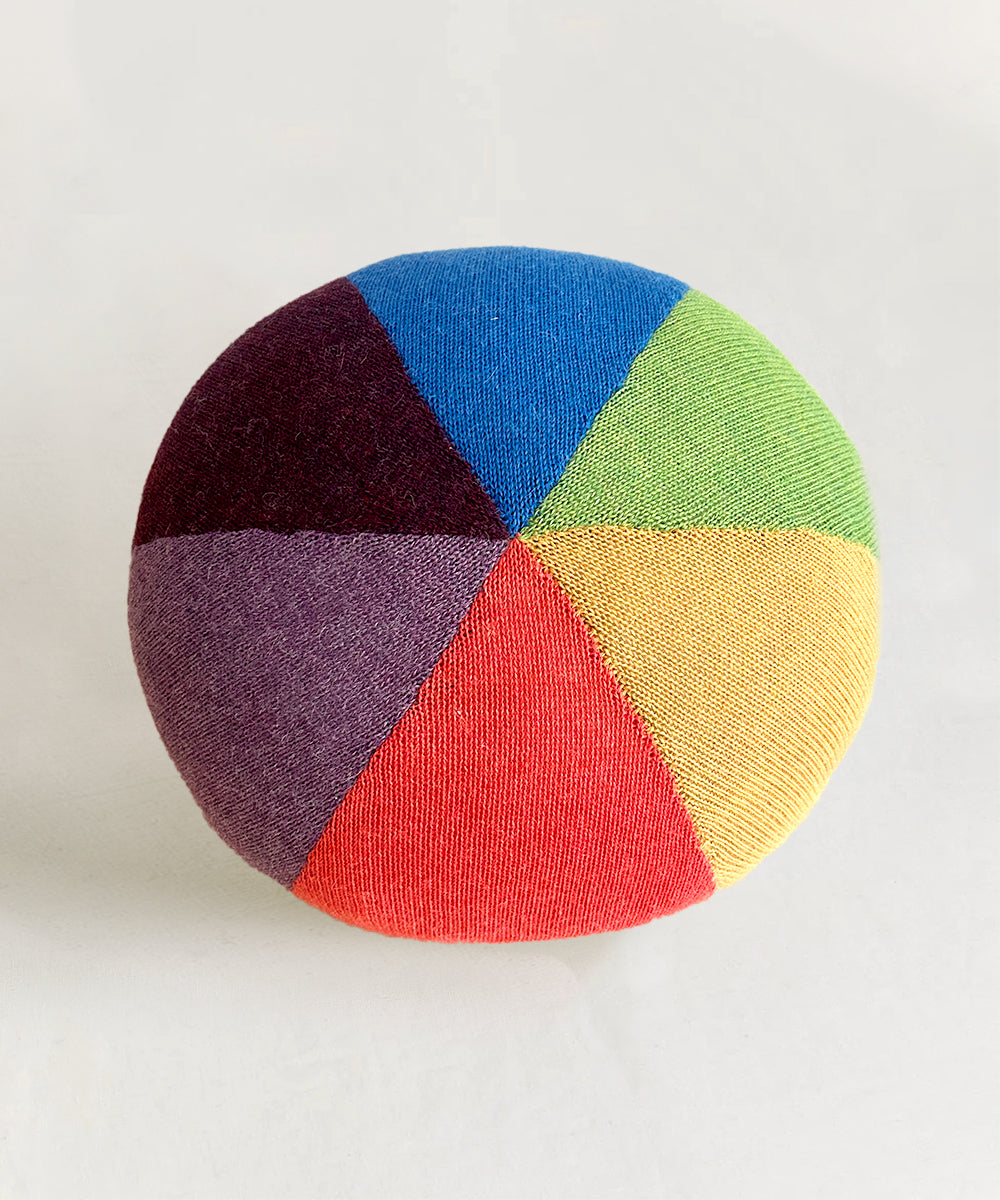 The Circus Ball - Rainbow is a round fabric ball with colorful, pie-shaped segments in blue, green, yellow, orange, red, purple, and burgundy.
