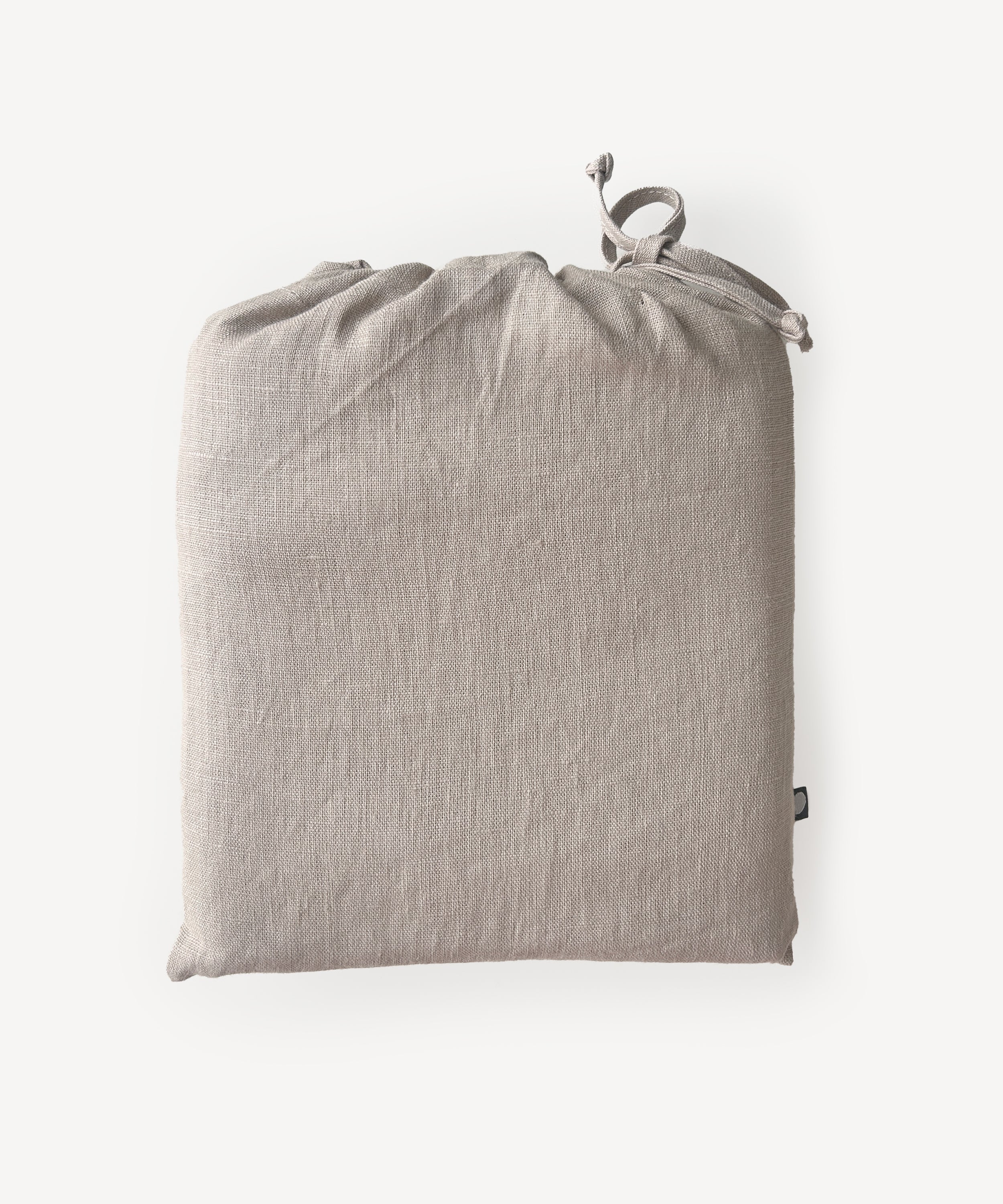A beige Crib/Toddler Fitted Sheet is folded and placed in a drawstring bag, displayed against a plain white background.
