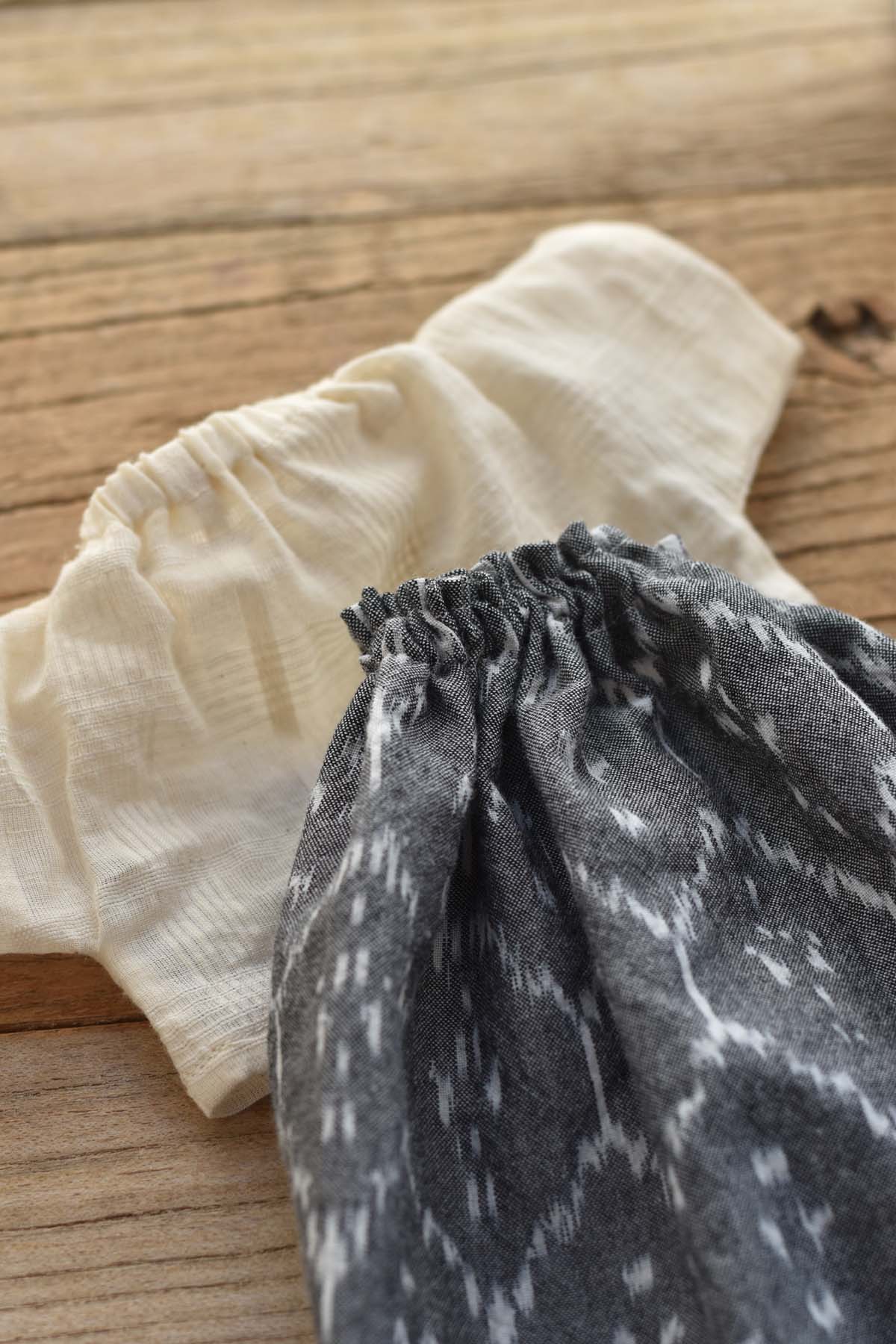 A small cream-colored shirt and the Fern the Frog – Ikat Field Skirt are laid out on a wooden surface.