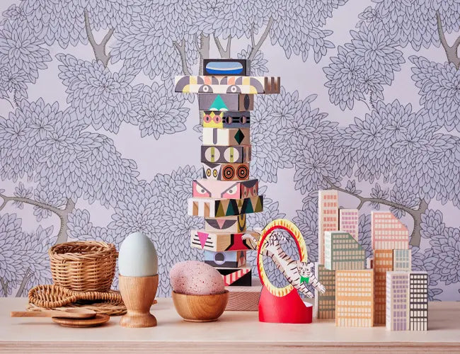 Colorful wooden blocks and baskets on a table with a patterned wallpaper background.