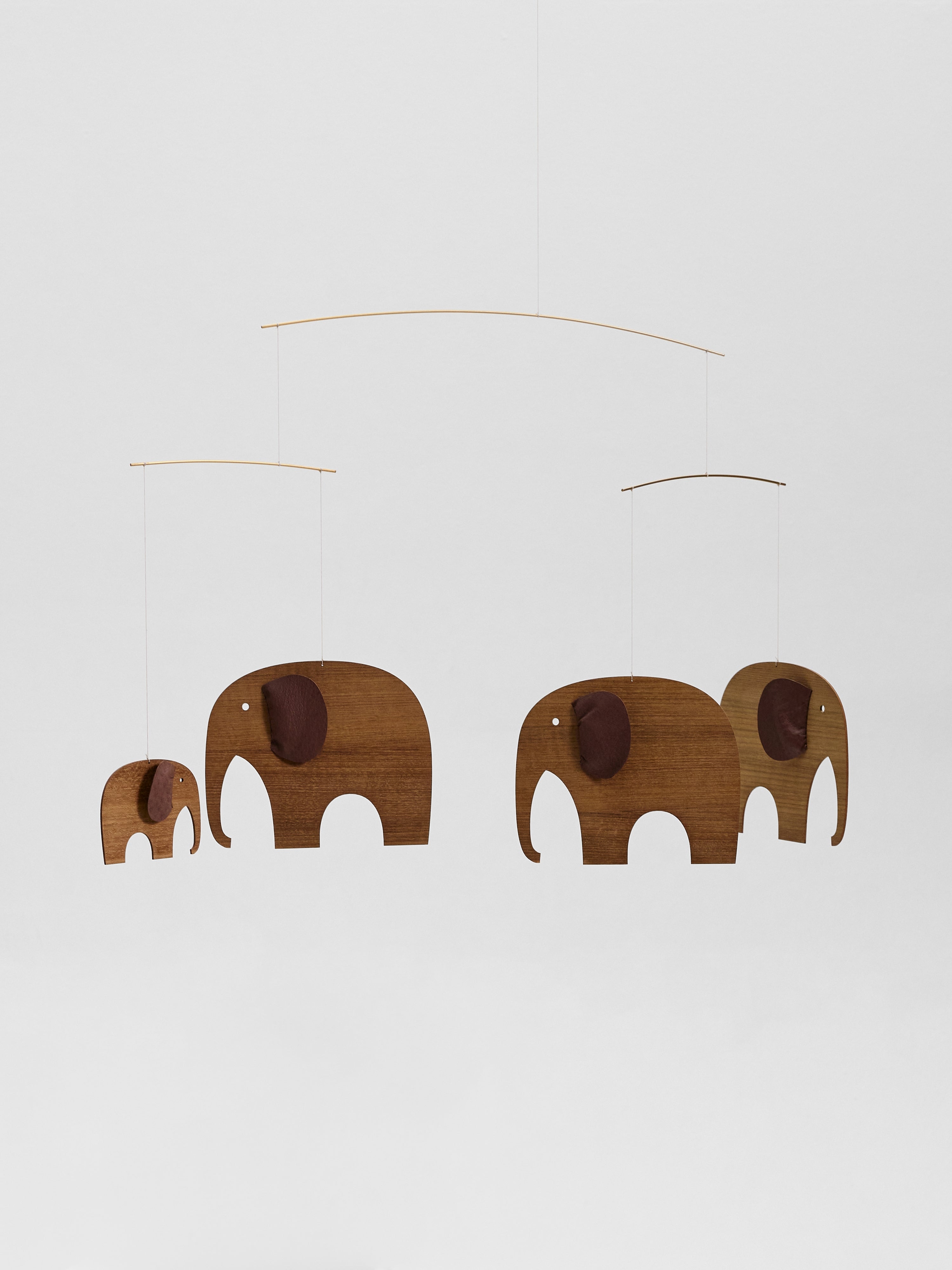 The Elephant Herd 4 | Wood features four wooden elephant-shaped mobiles suspended from thin wires against a plain white background.