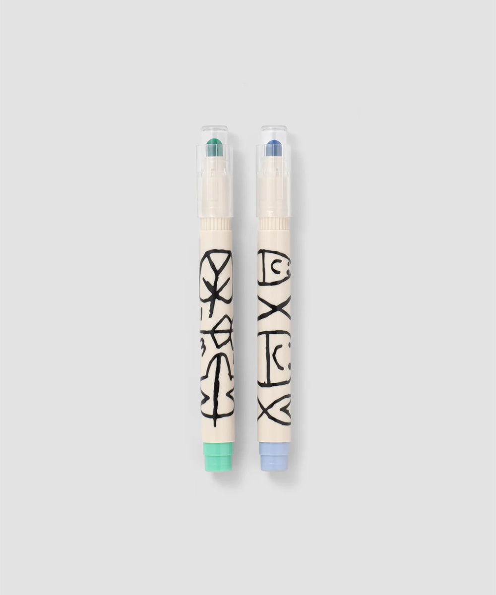 Two Le Well Rounded Markers with clear caps and abstract black designs on off-white bodies, displayed on a light gray background.
