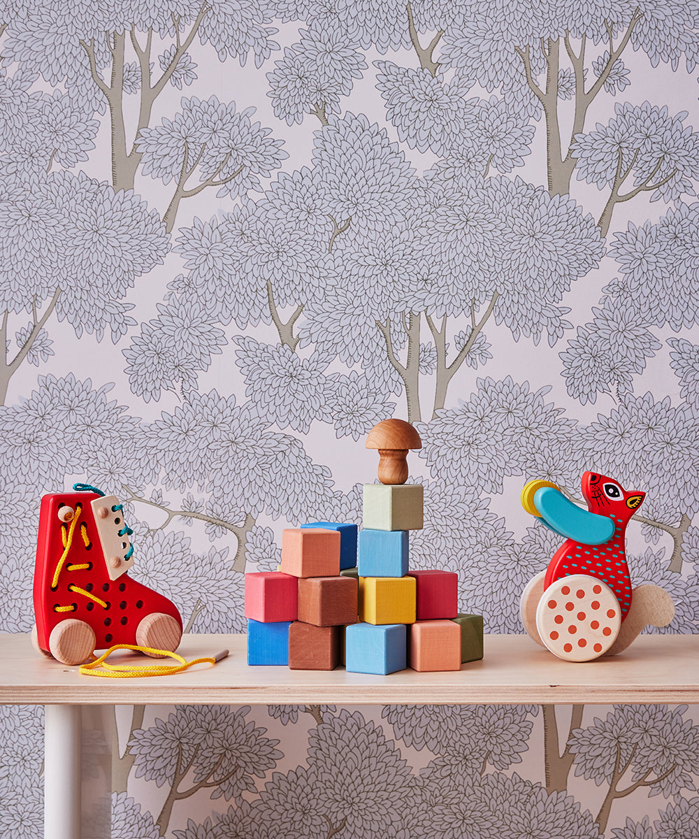 The Le Lacing Shoe sits on a table against floral-patterned wallpaper, surrounded by wooden toys and colorful blocks.