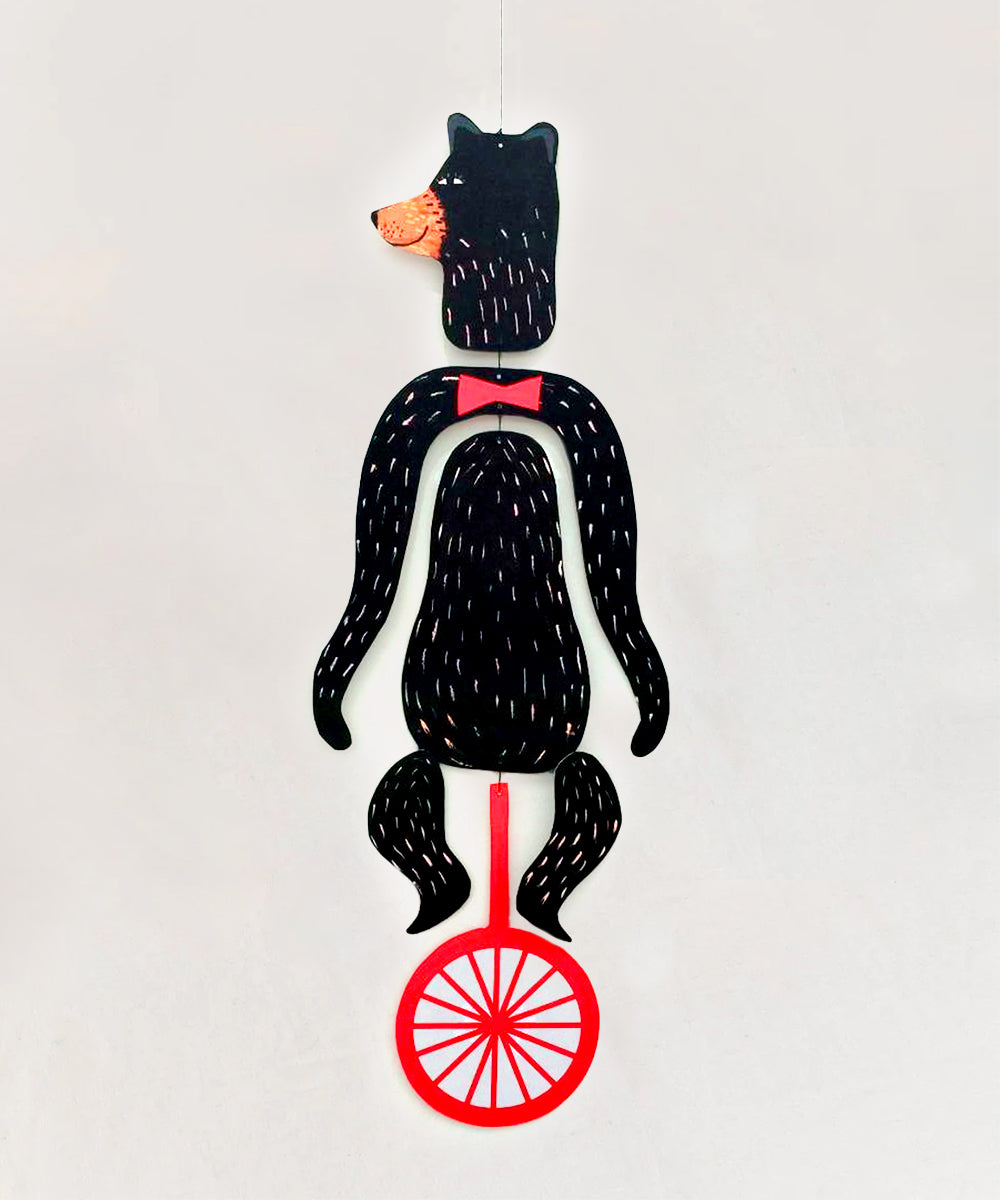 Le Mobile - Circus Bear: A hanging black bear puppet with a red bow tie, riding a red unicycle.
