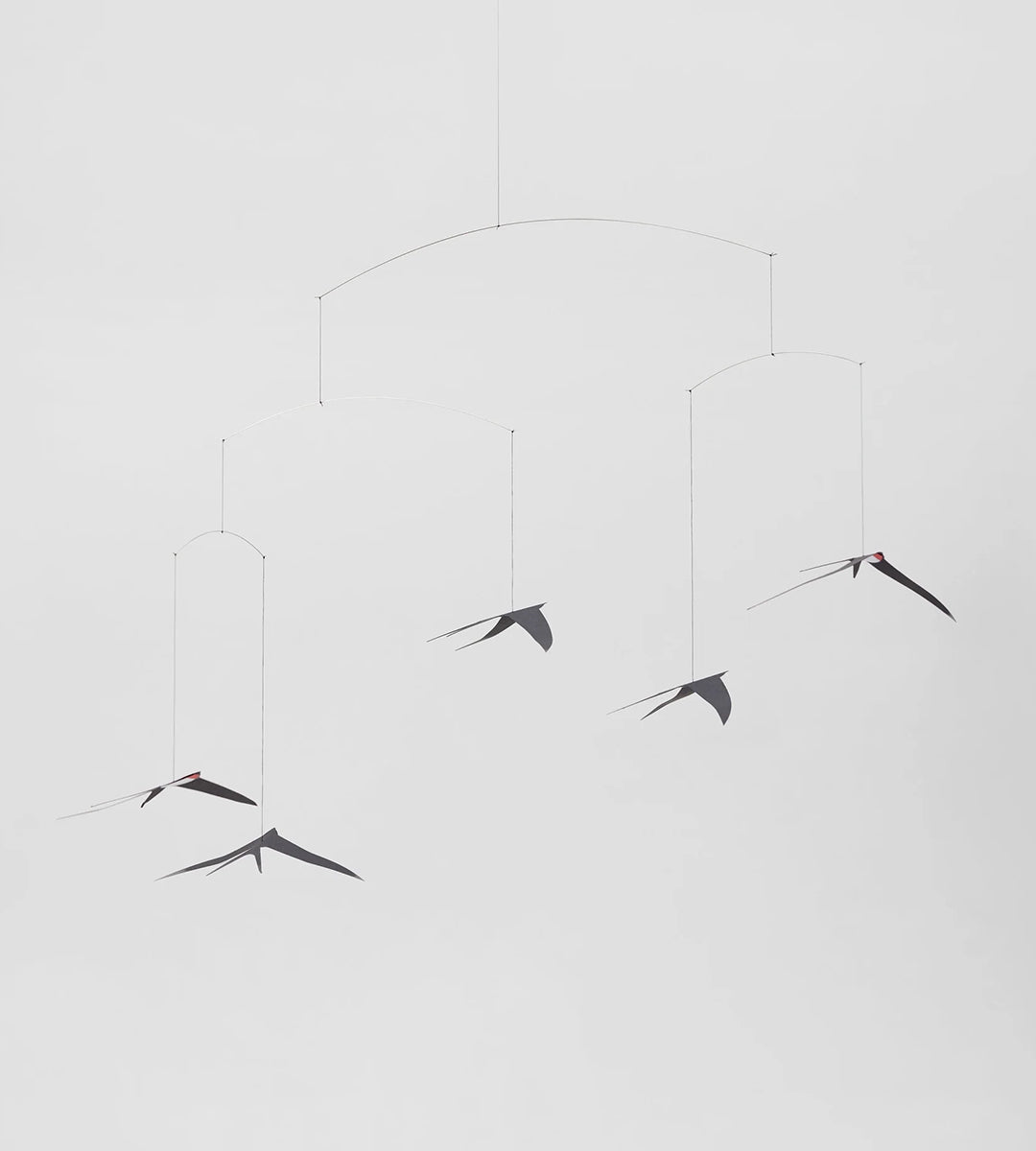 A hanging mobile featuring silhouettes of flying swallows in various positions against a white background.