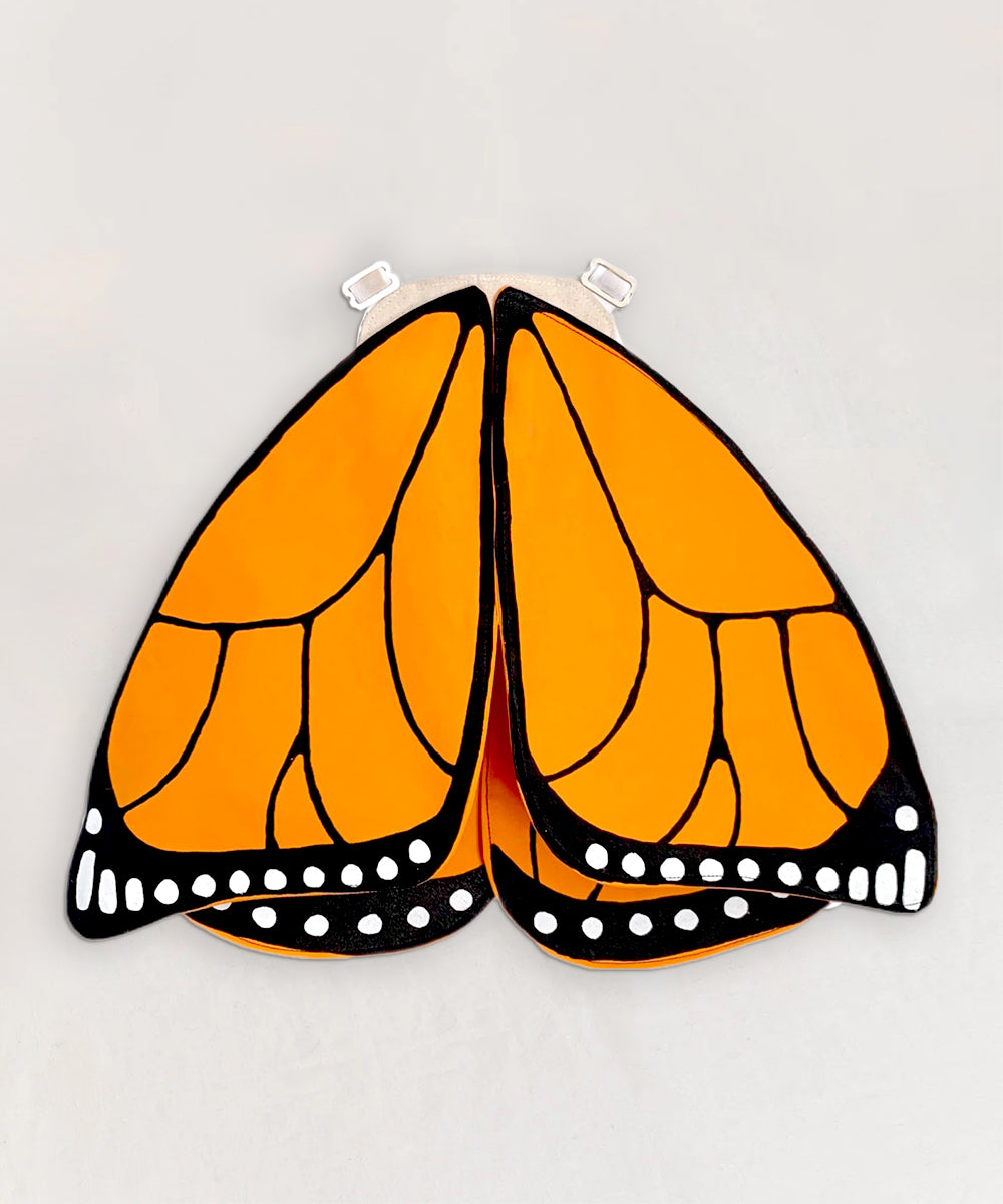Le Monarch Butterfly Wings Costume features bright orange and black wings with white spots, displayed flat on a light background.