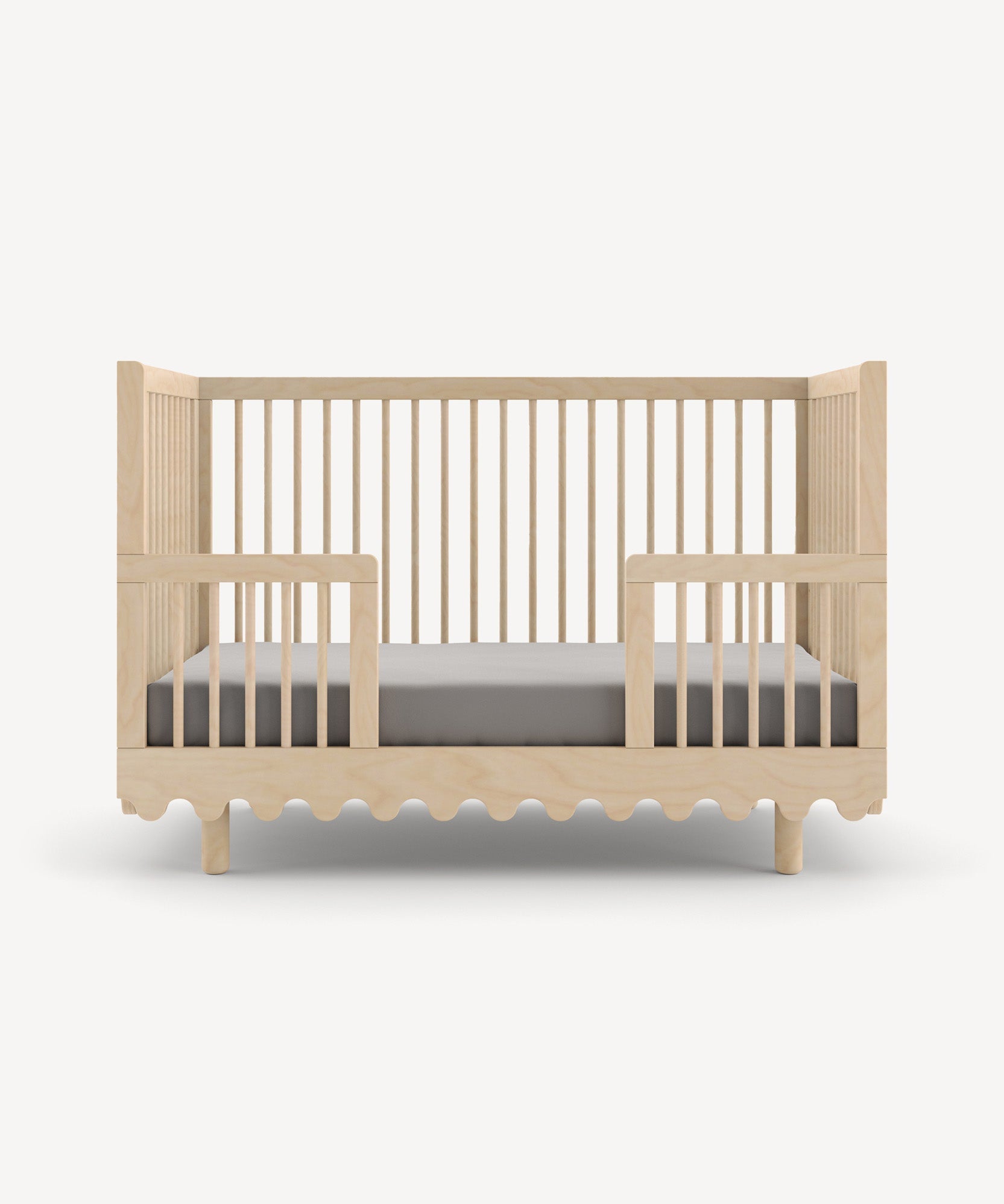 Moss Crib Conversion Kit with slatted sides, a wavy base design, shown with gray bedding.