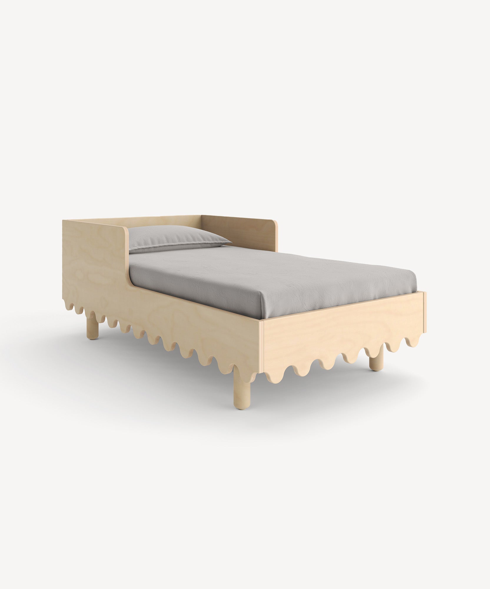 The Moss Toddler Bed, featuring a distinctive wavy edge design and paired with a gray mattress, is set against a simple backdrop.