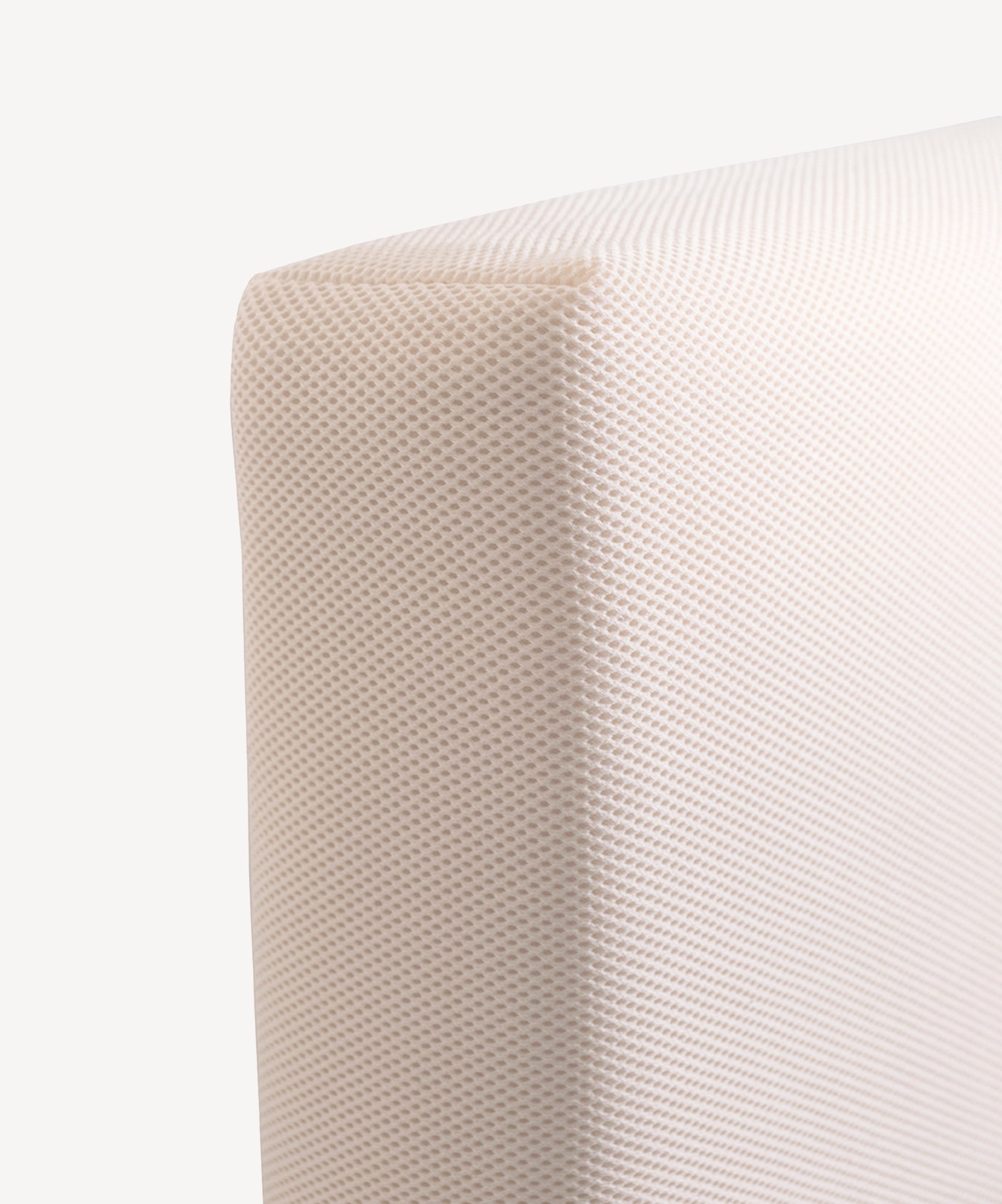 Close-up of the corner of a light beige textured Naturepedic Organic Breathable Baby Crib Mattress (2-Stage).