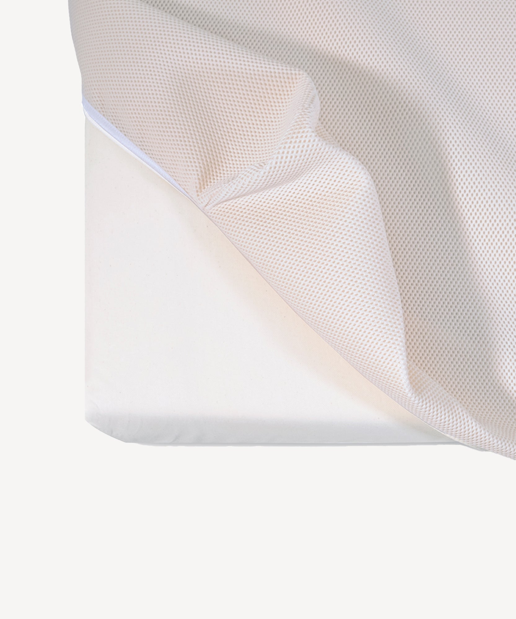 The Naturepedic Organic Breathable Baby Crib Mattress (2-Stage) shown with a corner of its white mesh fabric cover partially pulled back.
