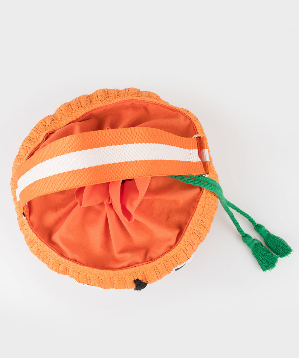 Le Pumpkin Basket Bag: round orange fabric bag with white-striped handle and green tassel drawstrings, viewed from above.