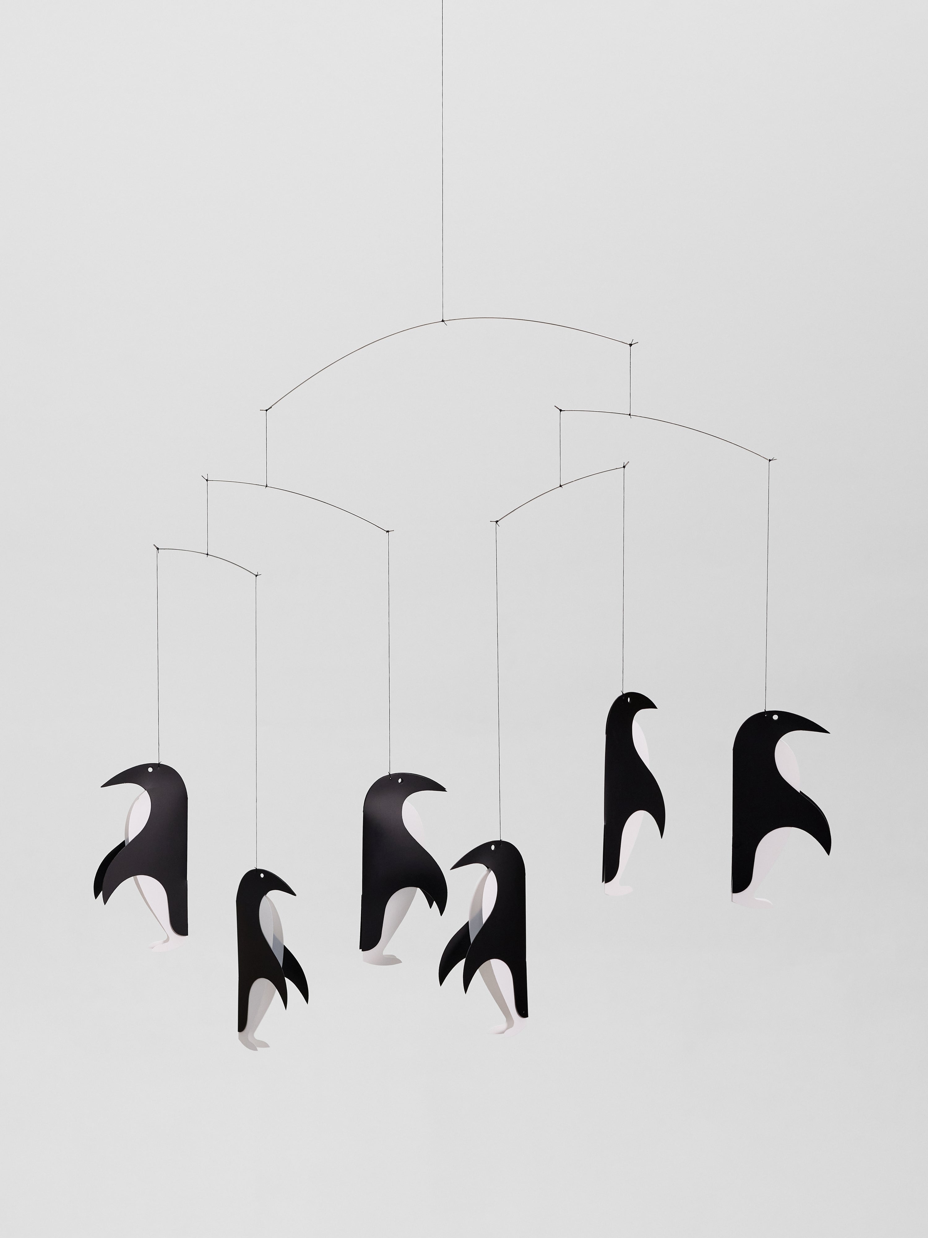 Penguin Talk features six black-and-white penguin cutouts suspended from thin wires, creating a charming mobile for any space.