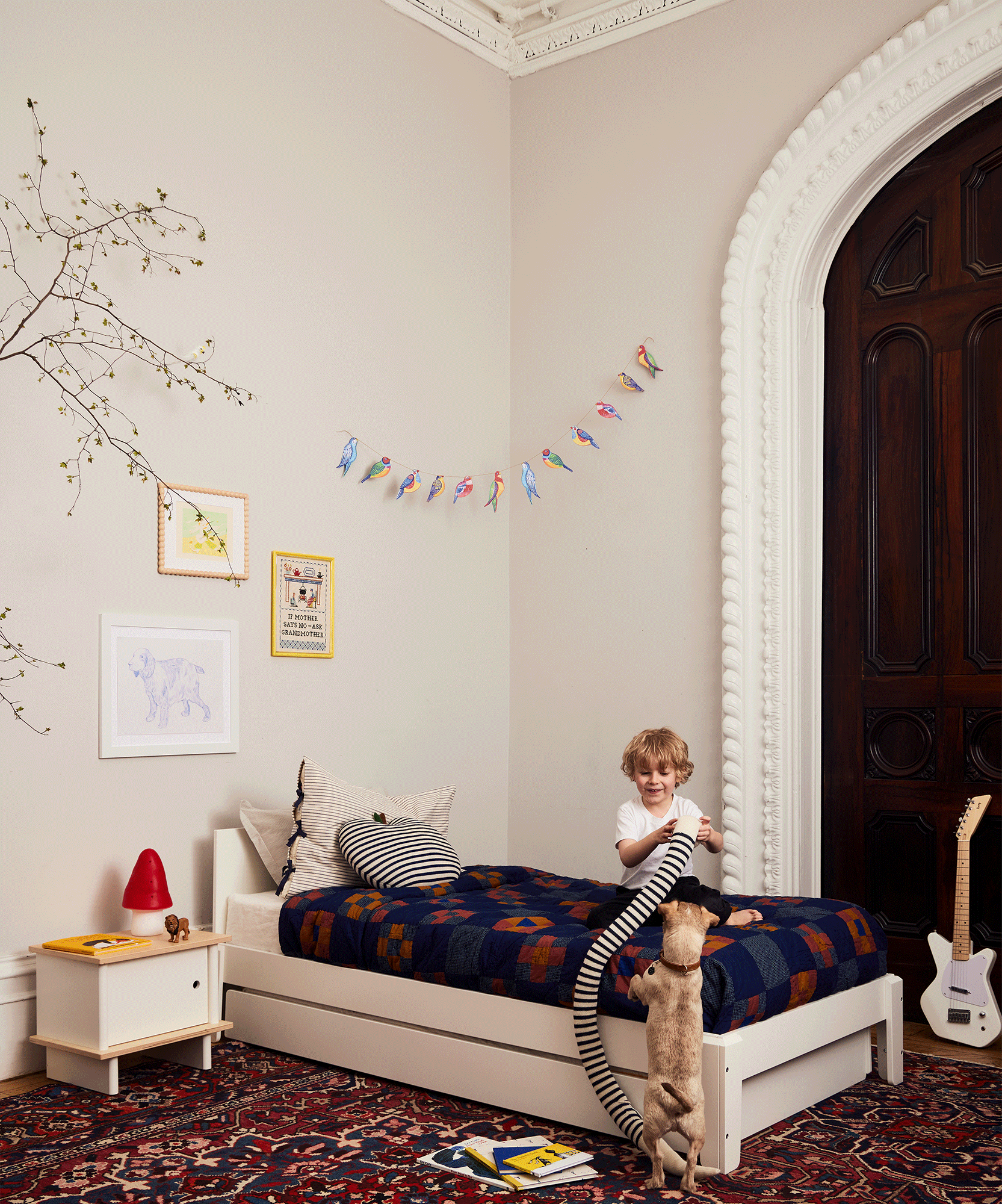 A child plays with a small dog in a cozy bedroom featuring the Perch Twin Bed, a colorful rug, and playful wall decor.