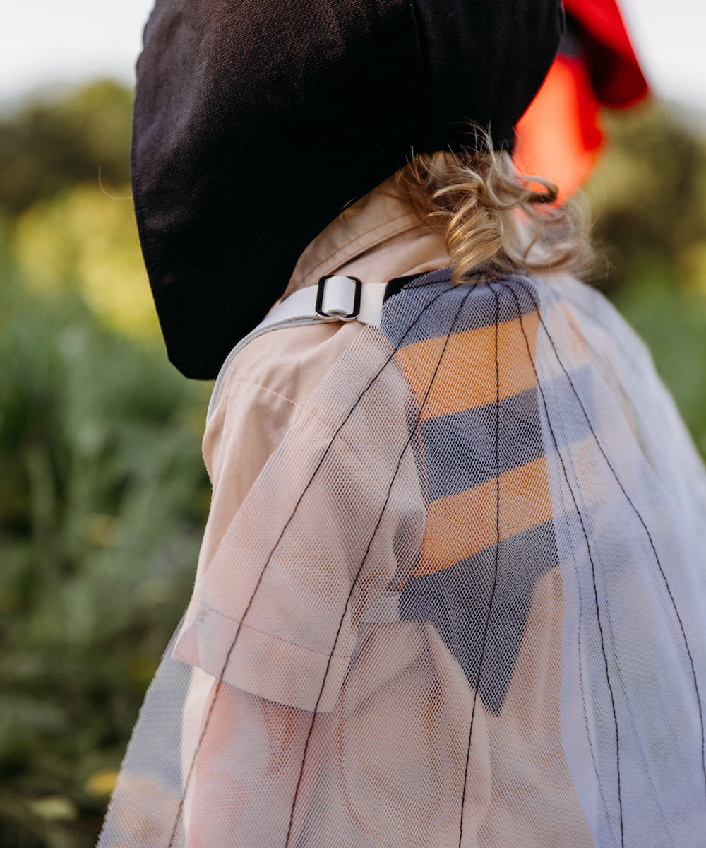 A child wears Bumble Bee Costume Wings and a black hat, standing sideways outdoors with greenery in the background.