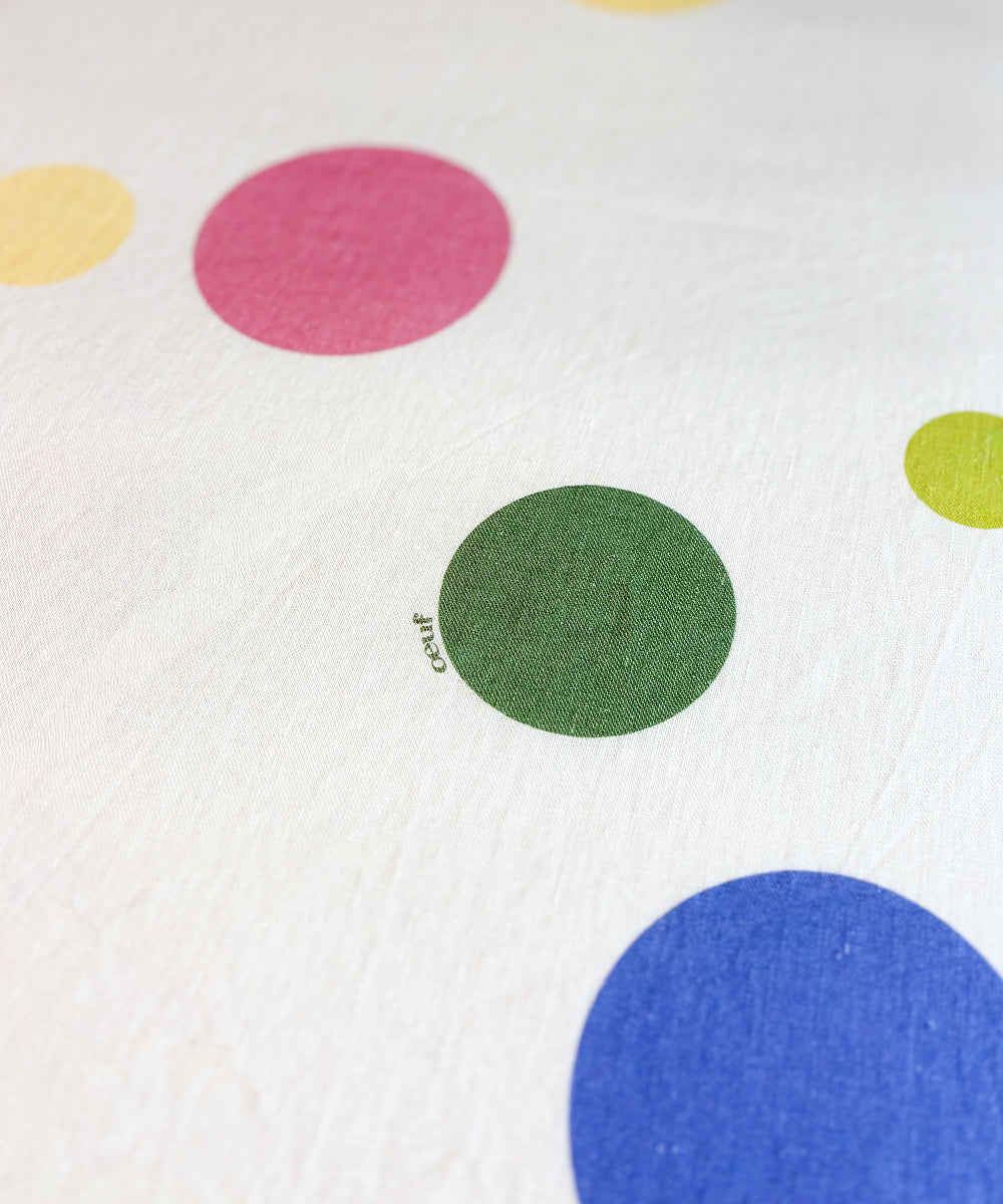 Printed Linen Crib Sheet in white fabric with scattered multicolored polka dots.