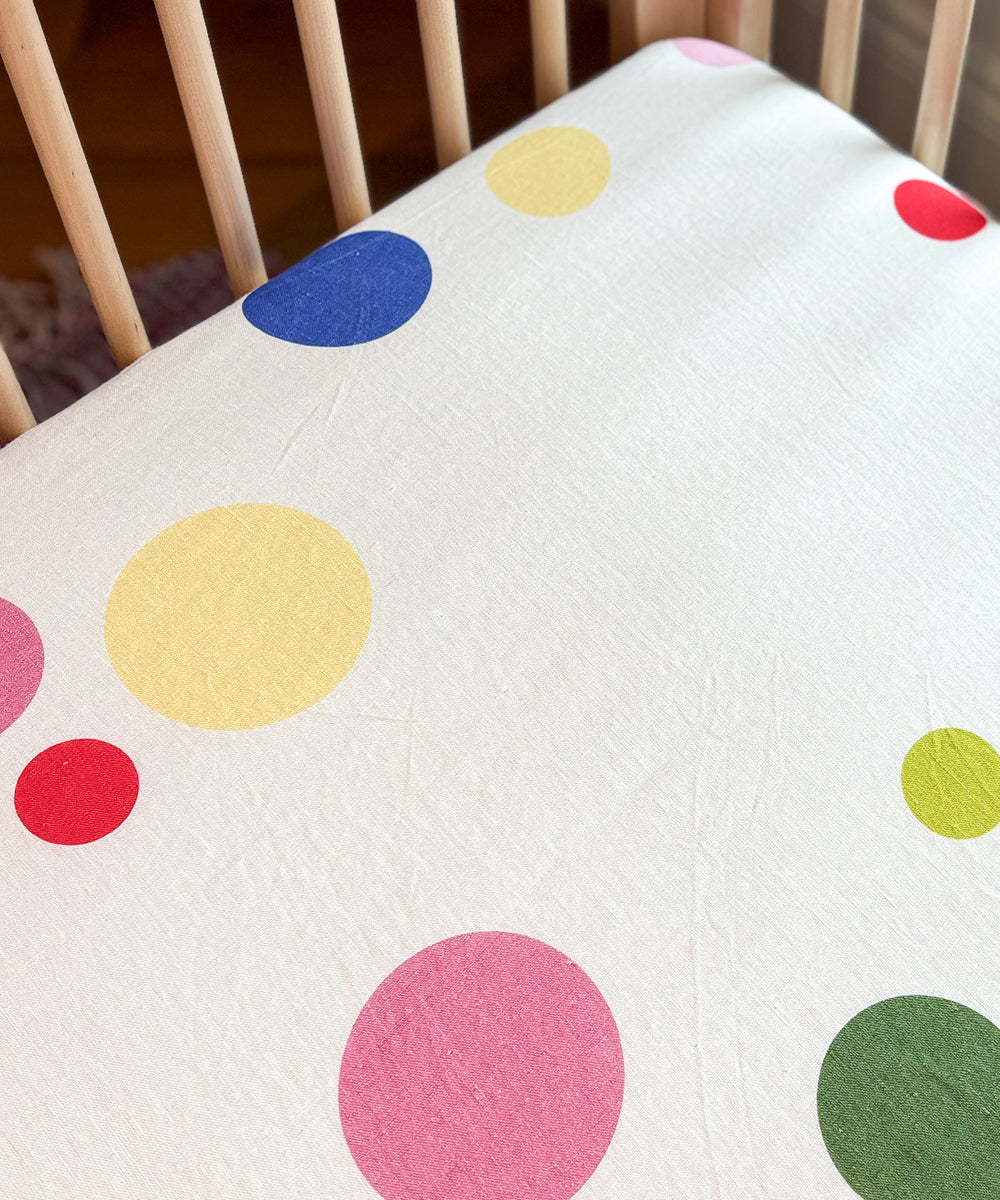 Printed Linen Crib Sheet featuring a pattern of colorful polka dots on a white background.