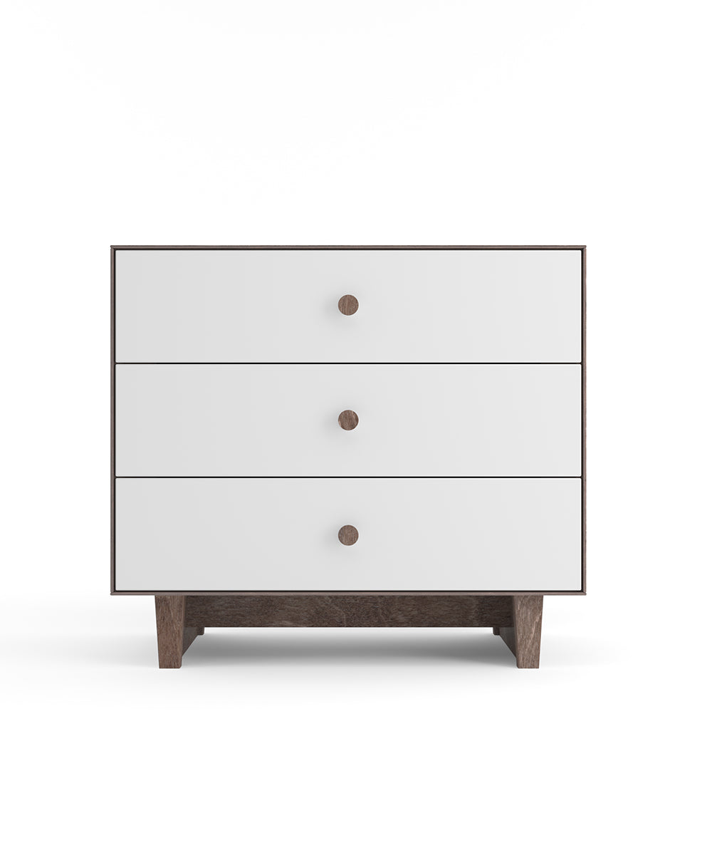 A white three-drawer dresser with wooden knobs and a dark wood base, against a plain white background.