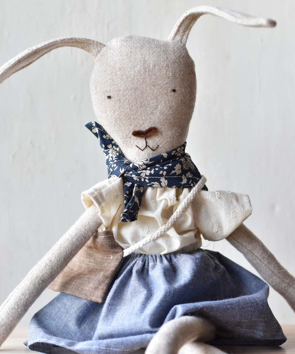 Ruthie le Rabbit is a handmade fabric doll dressed in a blue skirt, white blouse, and a floral scarf around her neck.