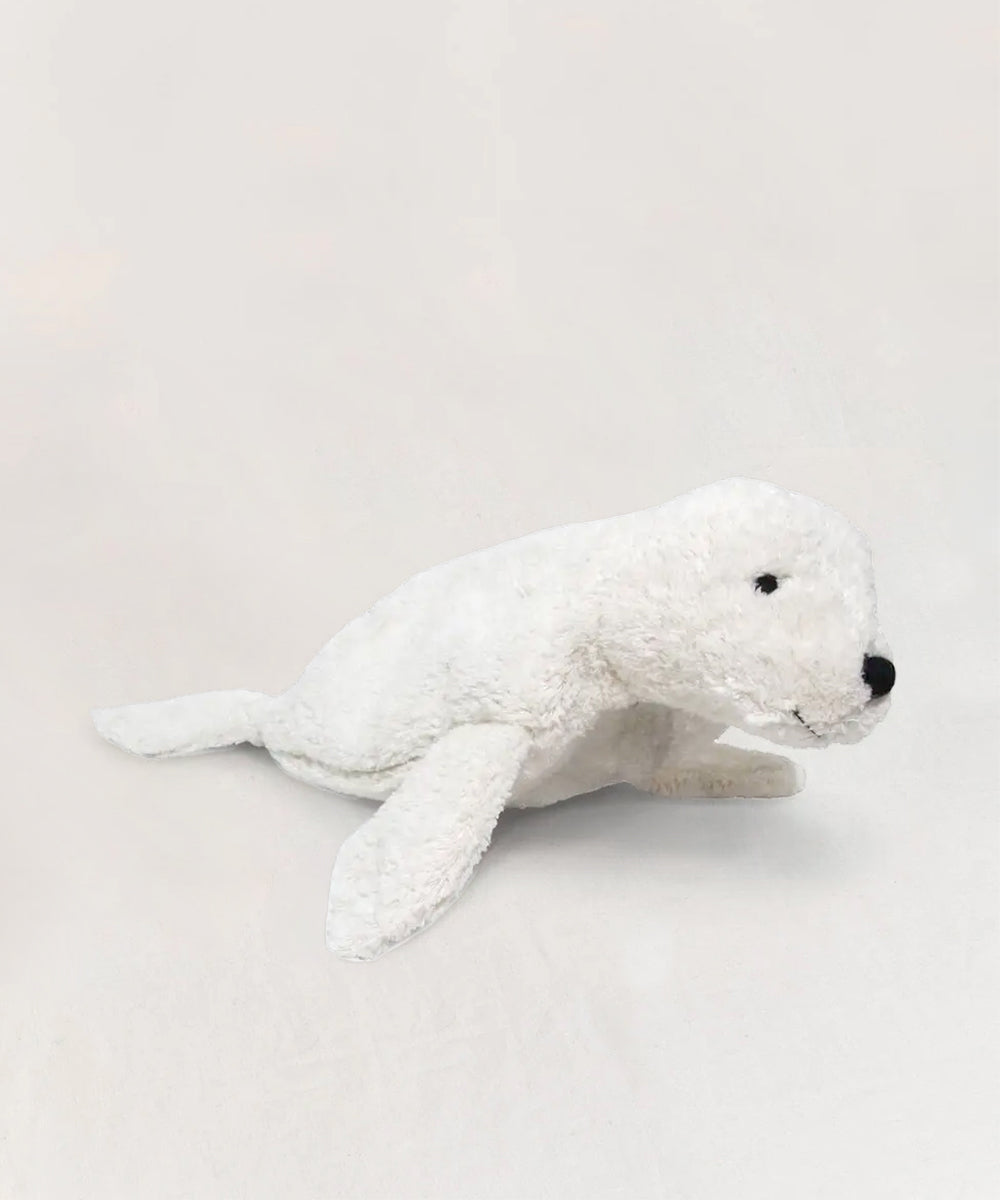 A white Seal plush toy with black eyes and nose is laying on a light background.