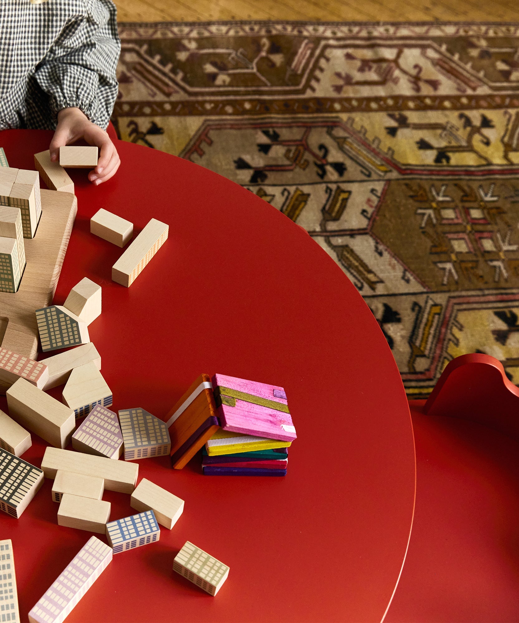 A child plays with block toys on the Moss Table, with a patterned rug underneath.