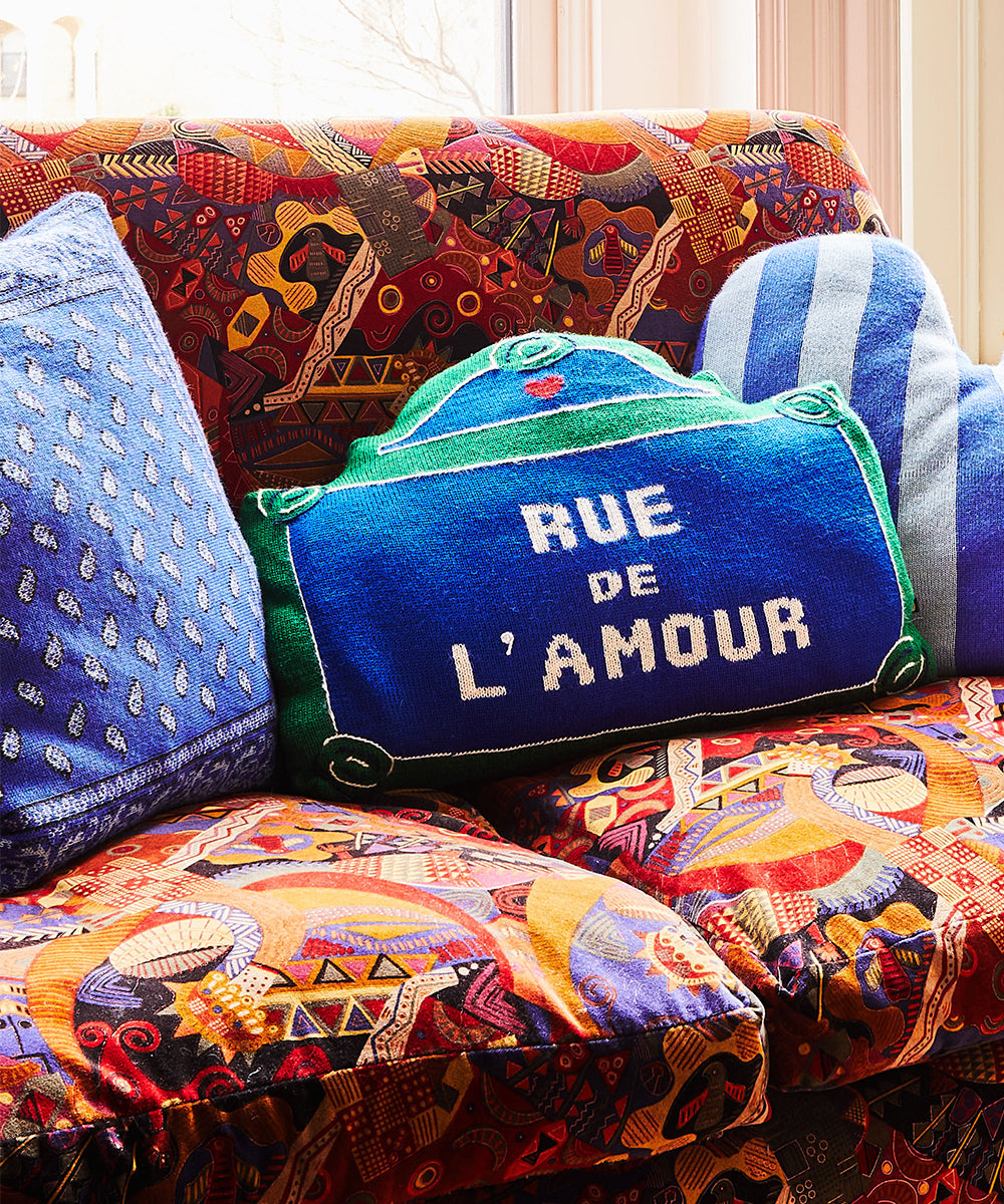 Cozy room featuring a colorful couch with patterned cushions and a Bandana Pillow and "RUE DE L'AMOUR" pillow.