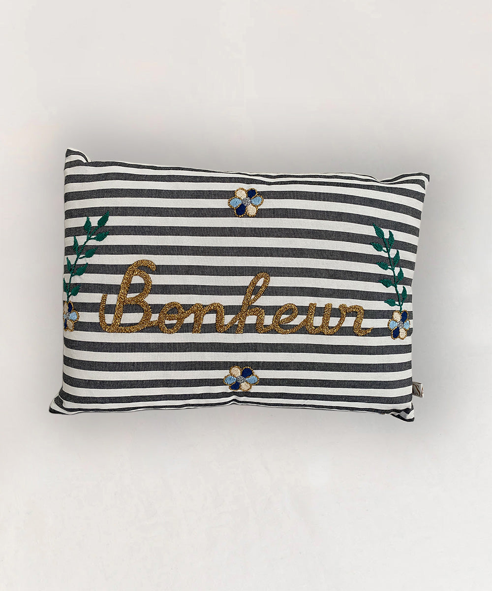 Le Embroidered Pillow - Striped Bonheur features black and white stripes, "Bonheur" embroidery, and decorative floral accents.