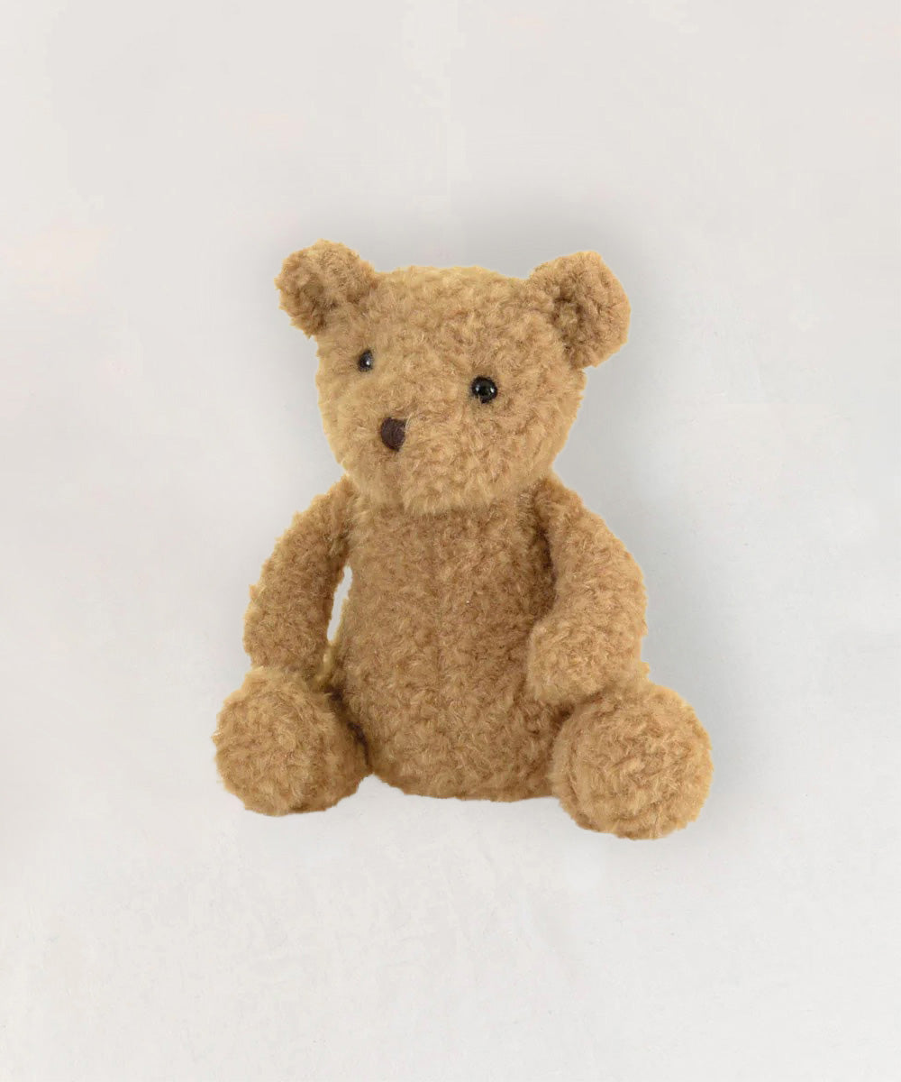 Eustache le Bear, a light brown, fluffy teddy bear, sits upright against a plain white background.