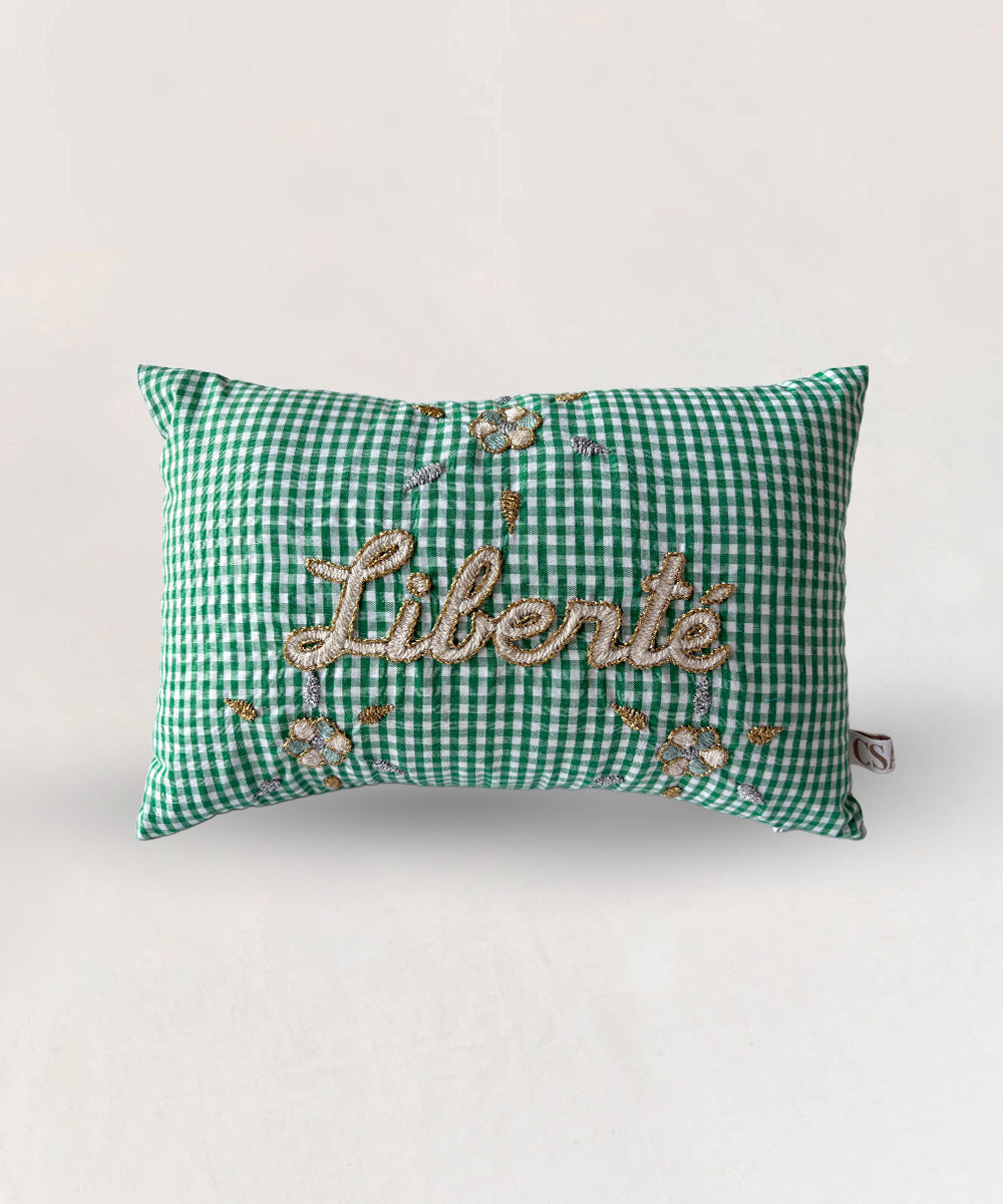 Le Mini Embroidered Pillow - Liberté: Green gingham pillow with "Liberté" and floral embroidery on the front, set against a plain background.