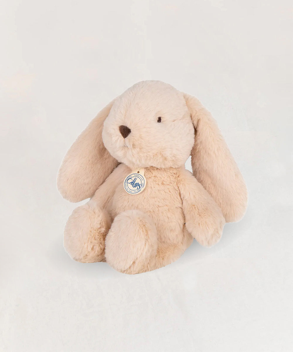 Bubbles le Bunny, a plush beige bunny with floppy ears and a round nose, sits on a white surface.