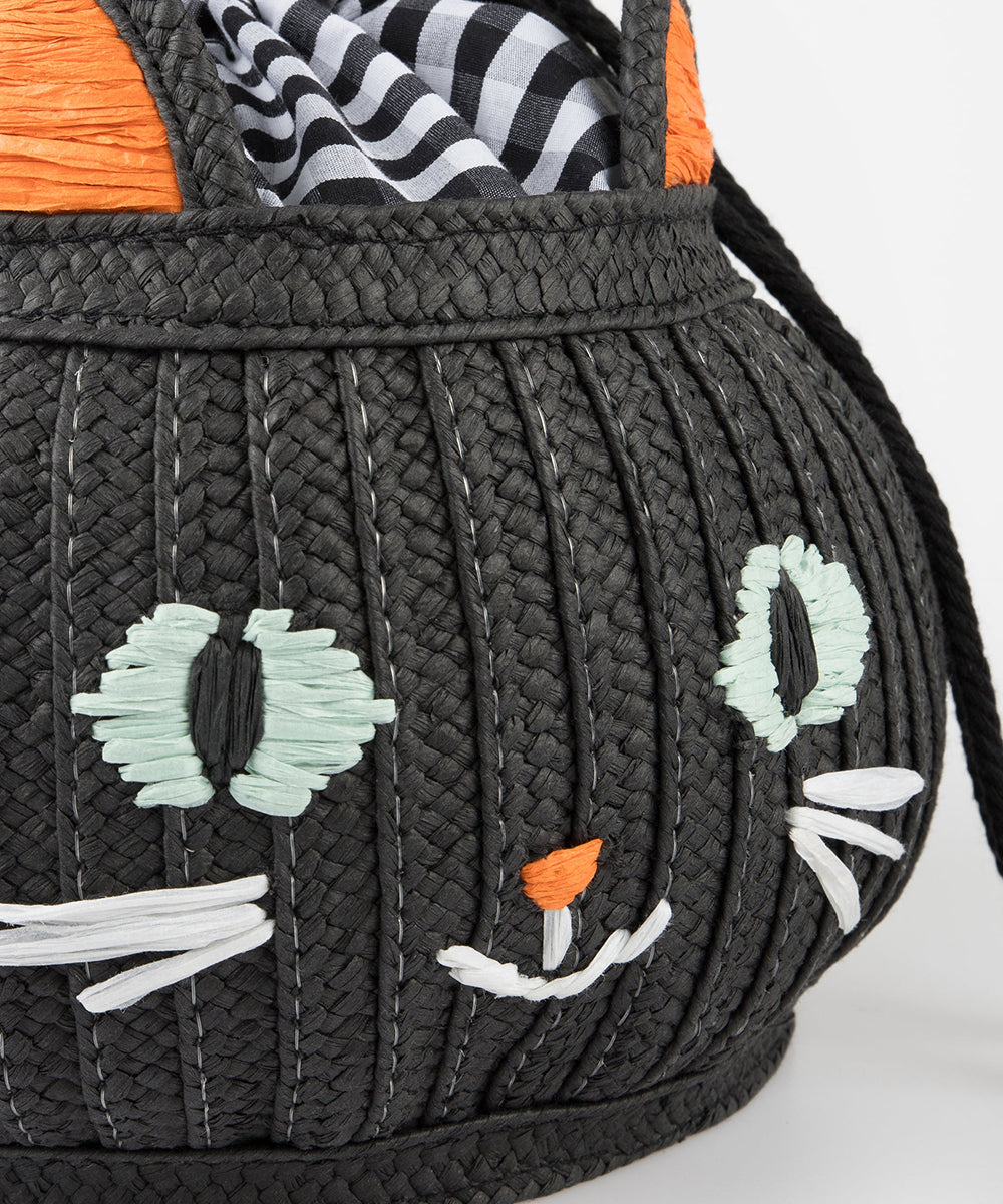 A close-up of the Le Cat Basket Bag, a woven black bag styled as a cat's face with striped fabric lining.