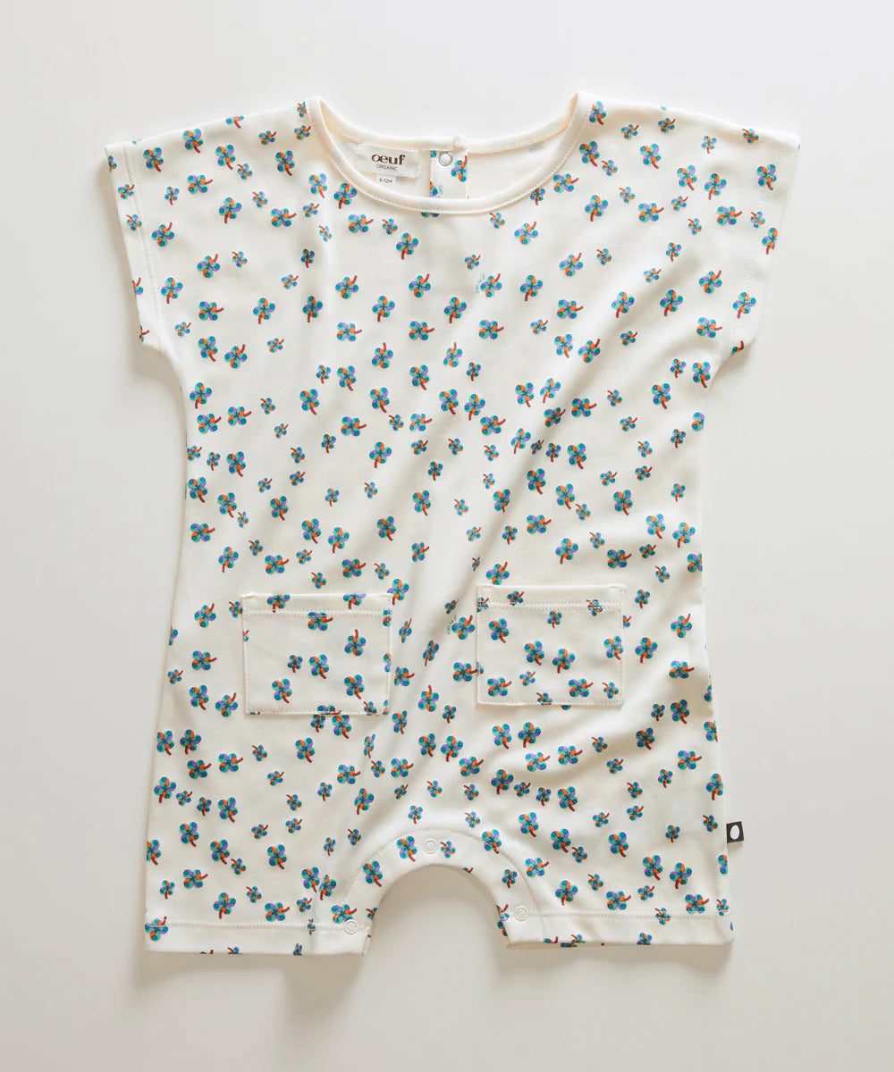 White baby romper with short sleeves featuring a pattern of small blue flowers and two front pockets.