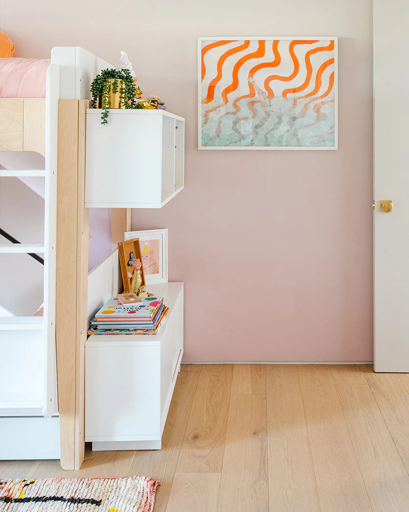 Childrens room with a bunk bed, bookshelves filled with books and plants, and a colorful wavy pattern artwork on a pink wall.