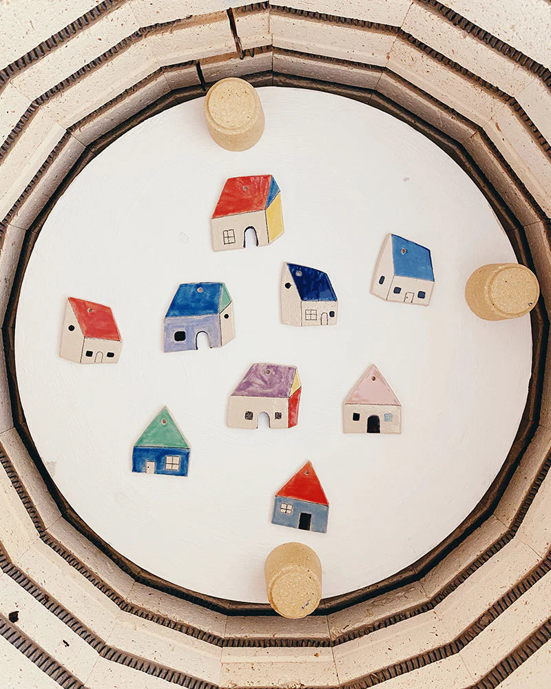 Small colorful ceramic house shapes arranged in a circular pattern inside a kiln.