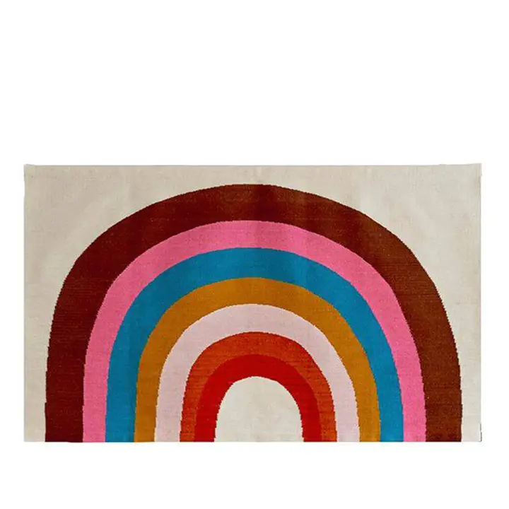 A rectangular rug with a rainbow design featuring arcs in red, orange, yellow, pink, blue, and brown on a beige background.