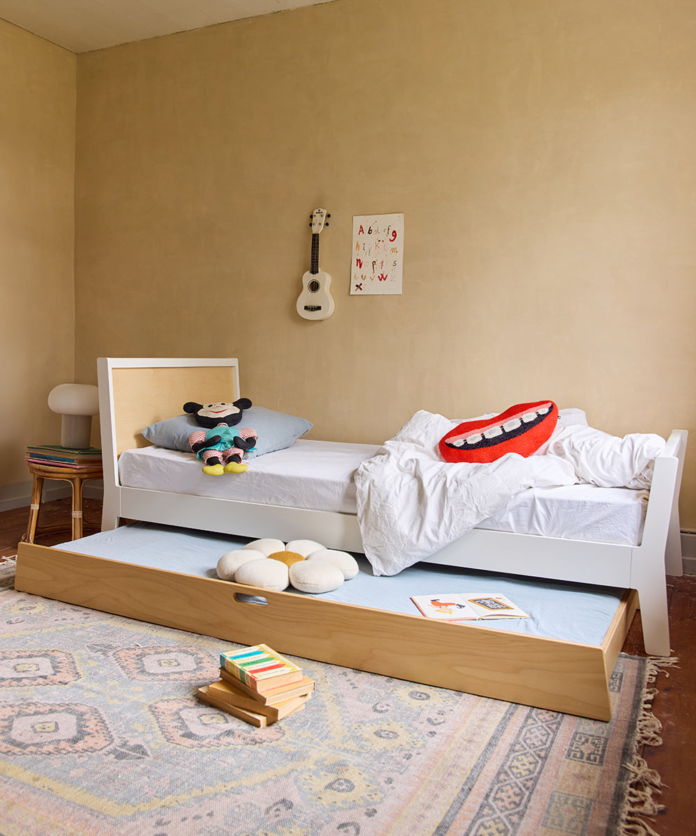 A cozy childrens room features the Sparrow Twin Bed and Trundle Bed, a guitar on the wall, playful cushions, and a colorful rug.