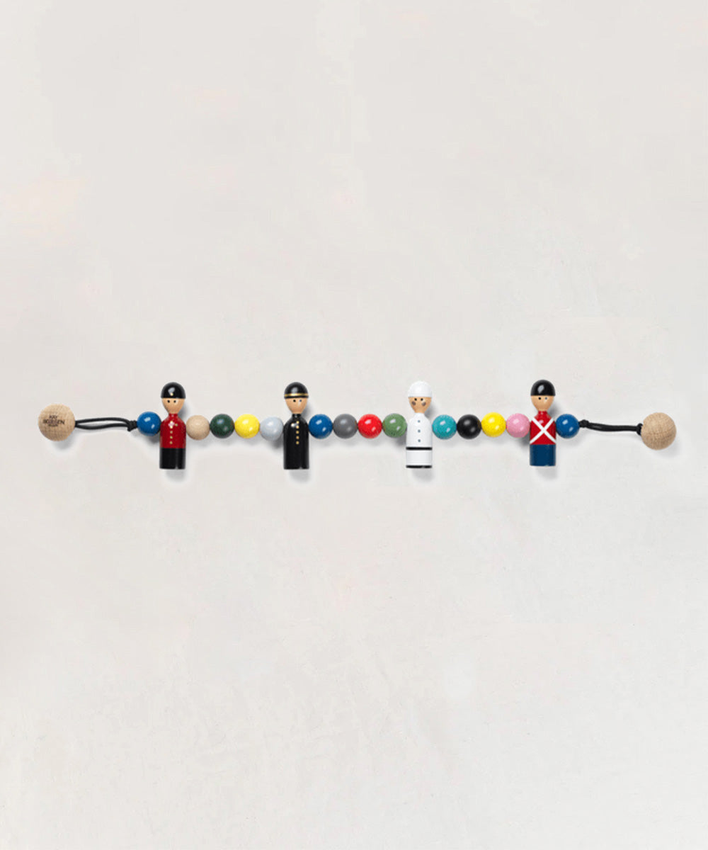 Le Pram Chain features four wooden figures dressed as guards, interspersed with colorful beads.