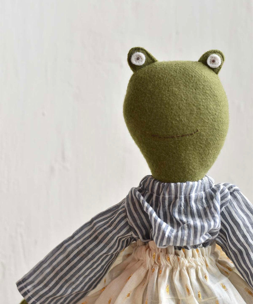 Fern le Frog doll in a striped shirt, scarf, and sparkle cream skirt, shown against a light background.