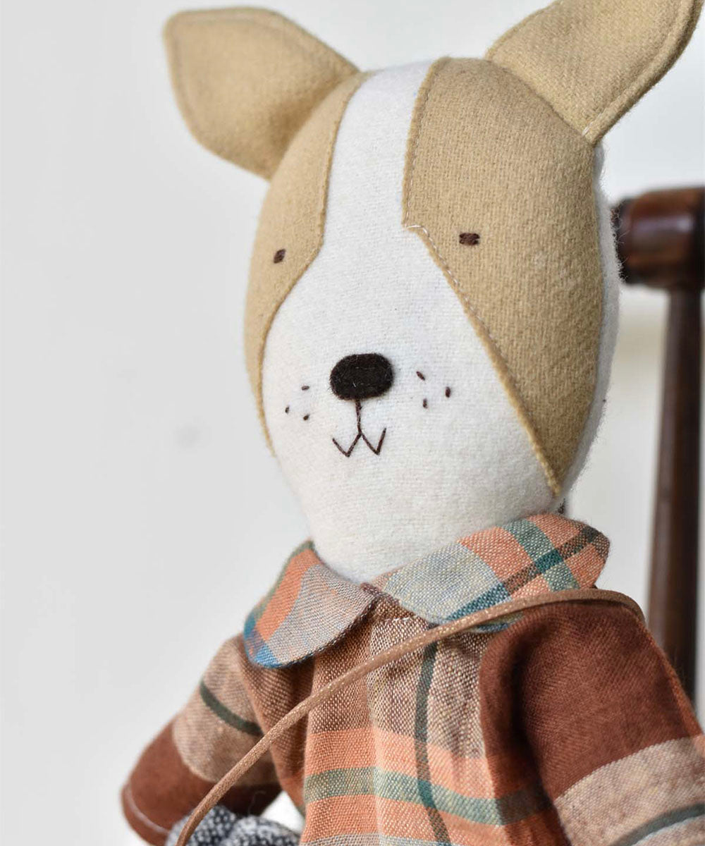 Fig le Frenchie Dog plush with brown and white face, wearing an Ojai Orchard Gather Dress, sitting on a wooden chair.