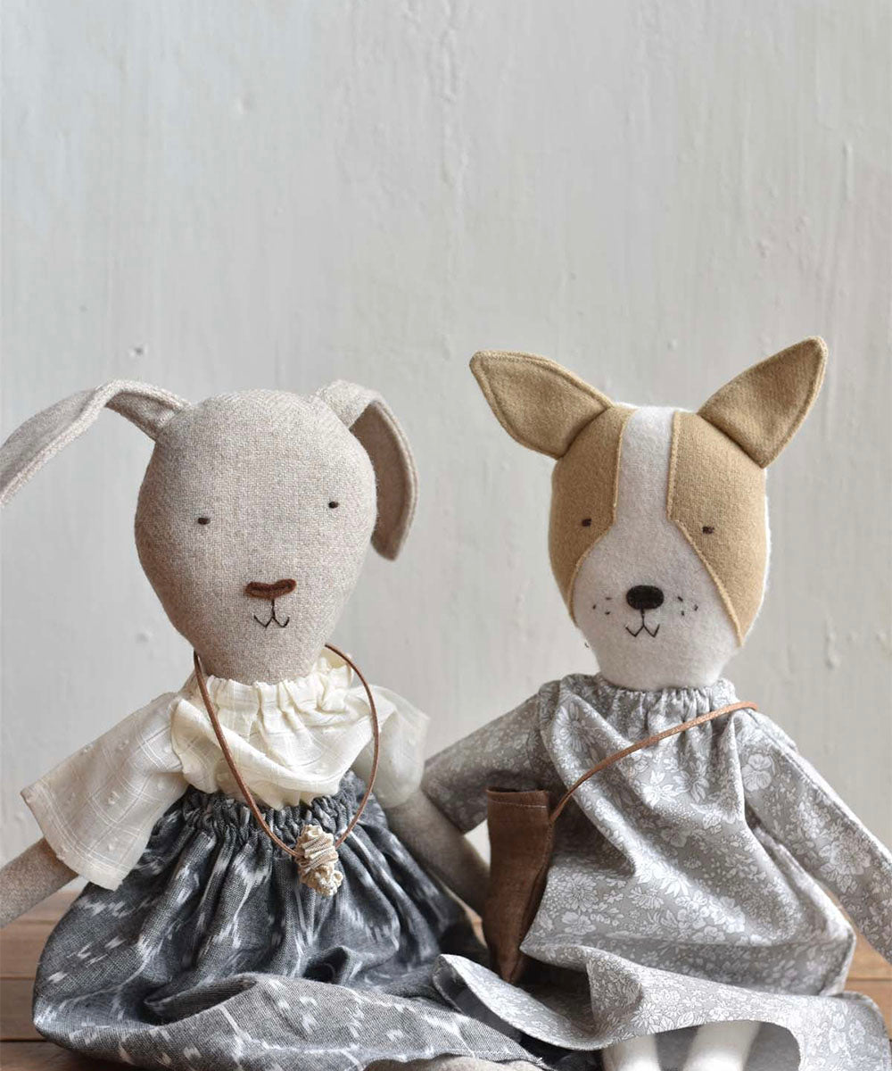 Ruthie le Rabbit, wearing an ikat skirt, is a fabric animal doll sitting on a wooden surface.
