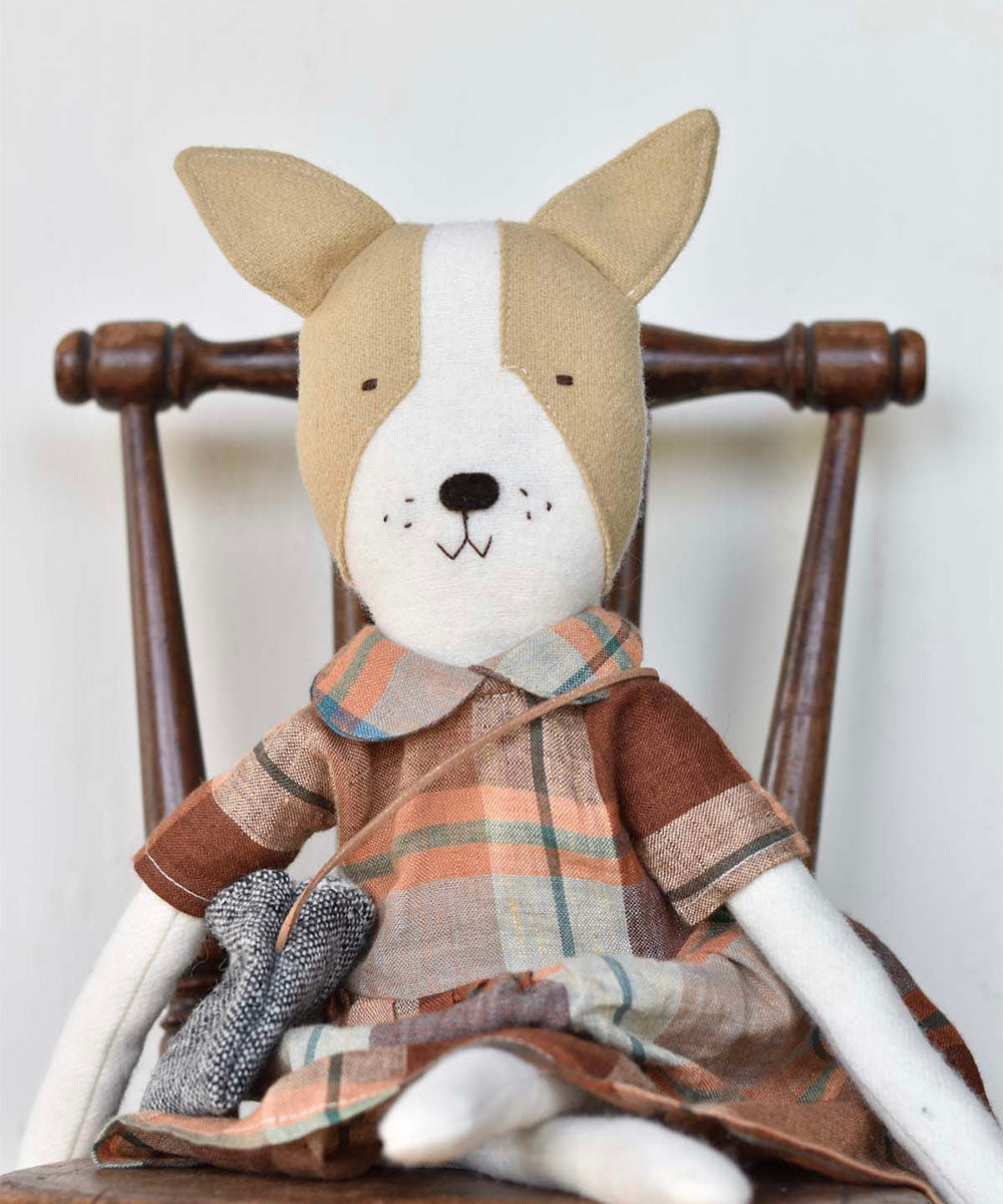 Fig le Frenchie Dog in an Ojai Orchard Gather Dress sits on a wooden chair, holding a small gray toy mouse.