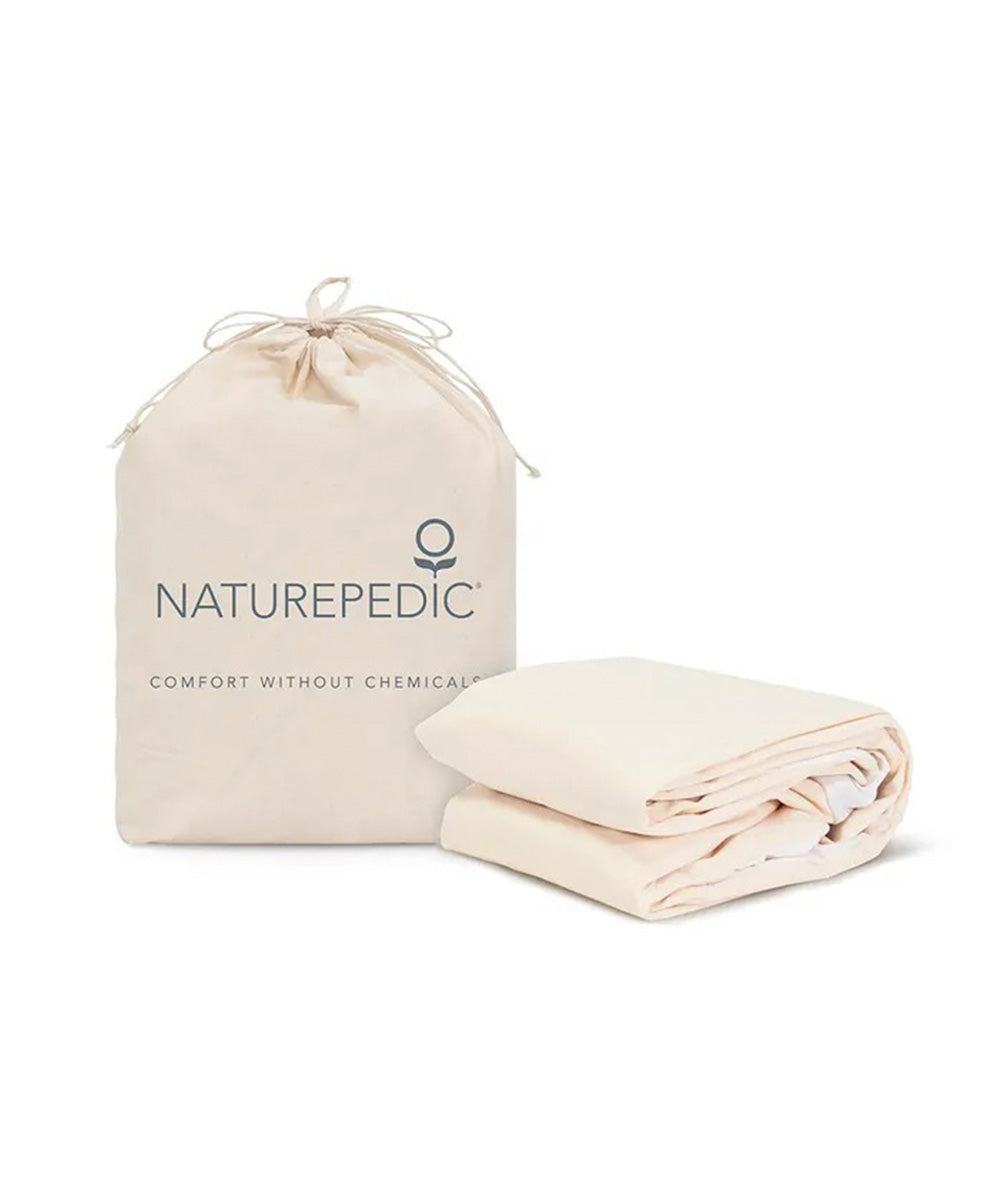 A folded cream-colored Organic Waterproof Kids Mattress Protector Pad sits beside a matching drawstring bag labeled "Naturepedic.