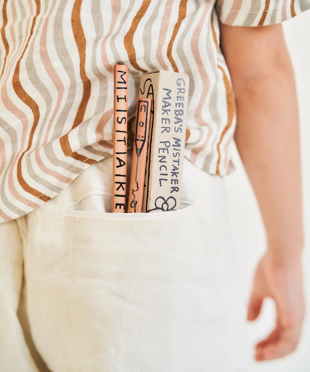 A child with two large Le Mistake Maker Pencils labeled "MISTAKE" and "MISTAKE MAKER" sticking out of a pocket.