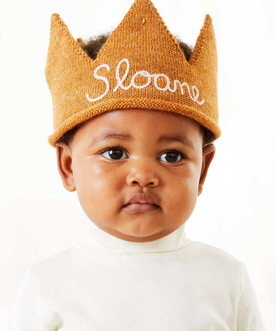 Baby wearing the Personalized Gold Crown - White with "Sloane" on it, dressed in a white shirt and looking forward.